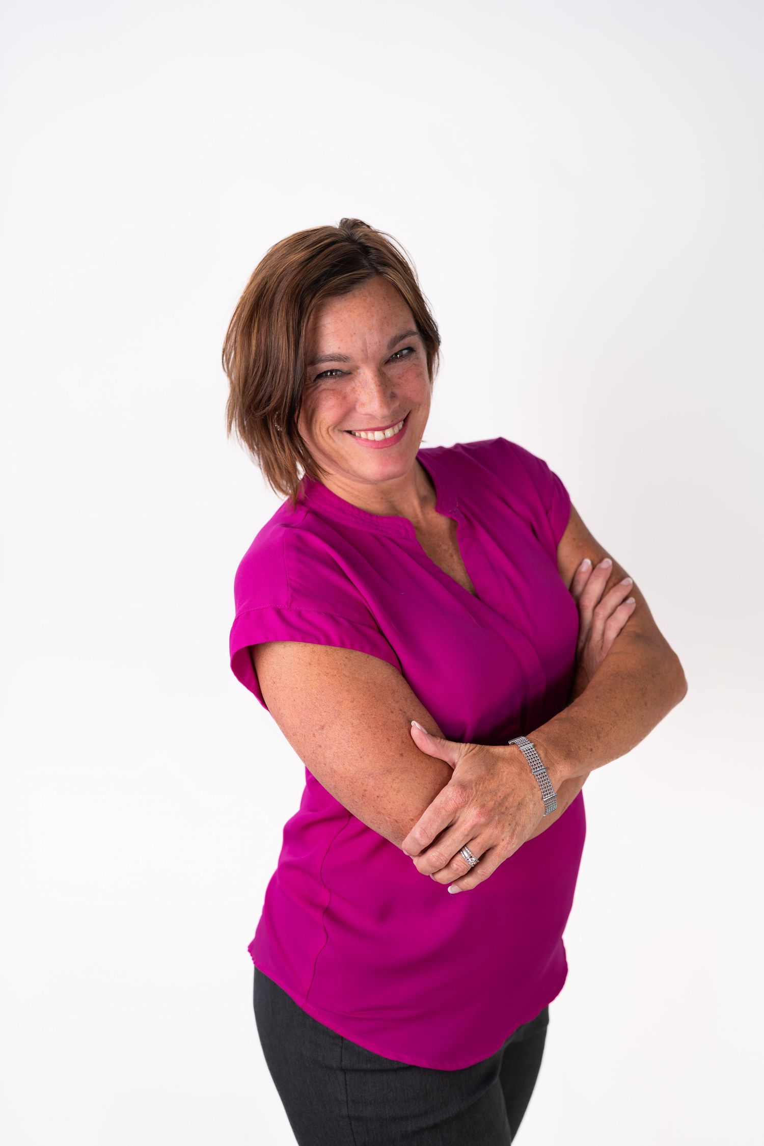 Person in magenta top poses expressively against white studio background.
