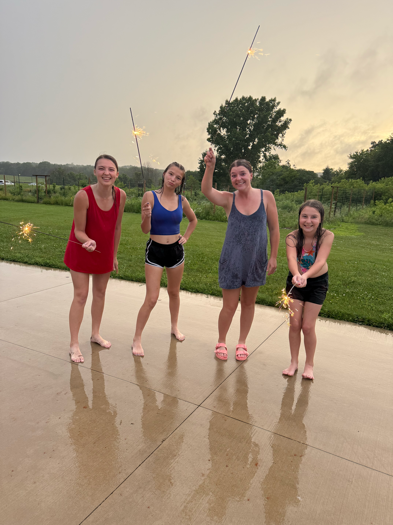 Friends posing together on wet pavement during sunset with fishing rods.