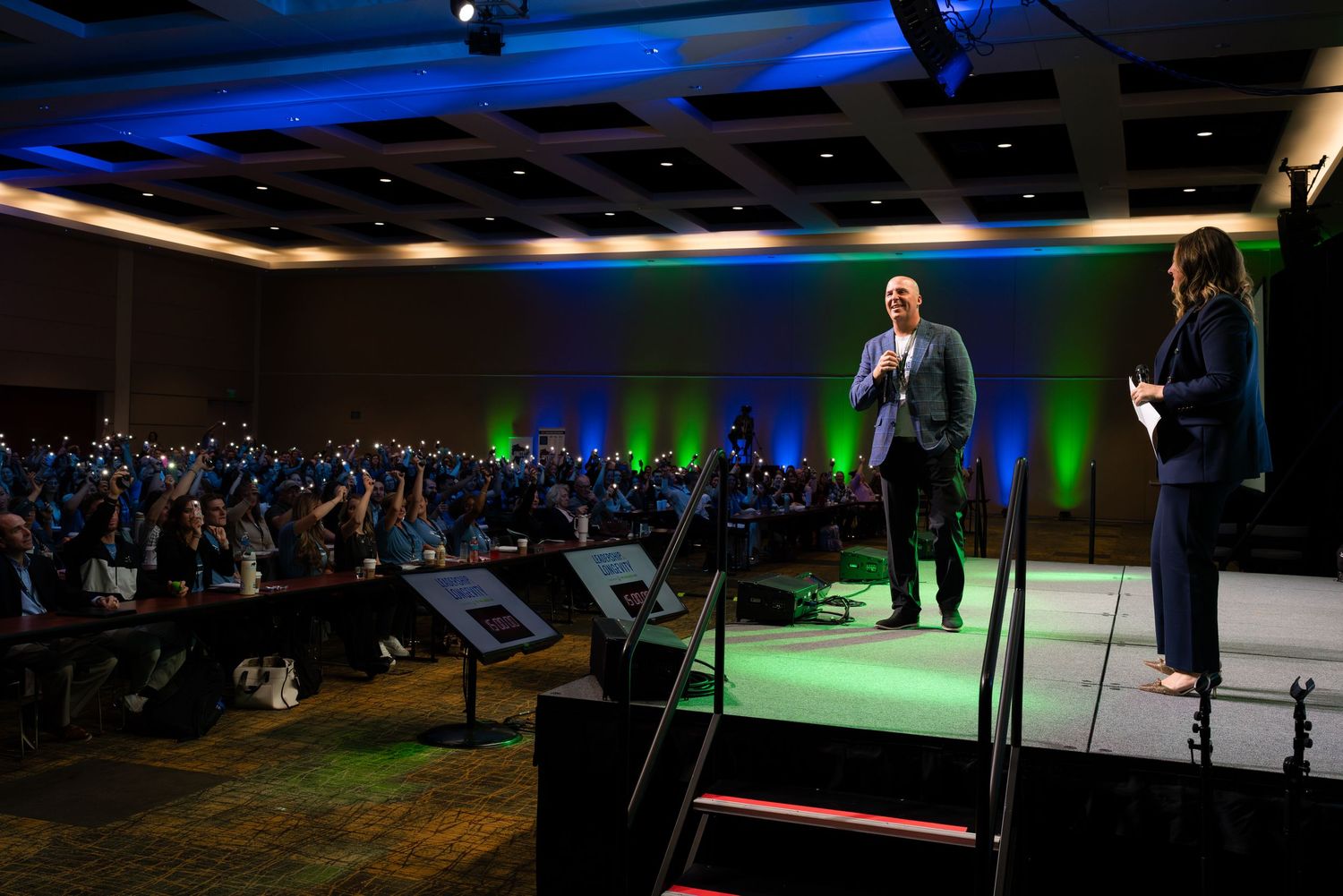 Wide shot of conference venue with stage lighting and audience seating.