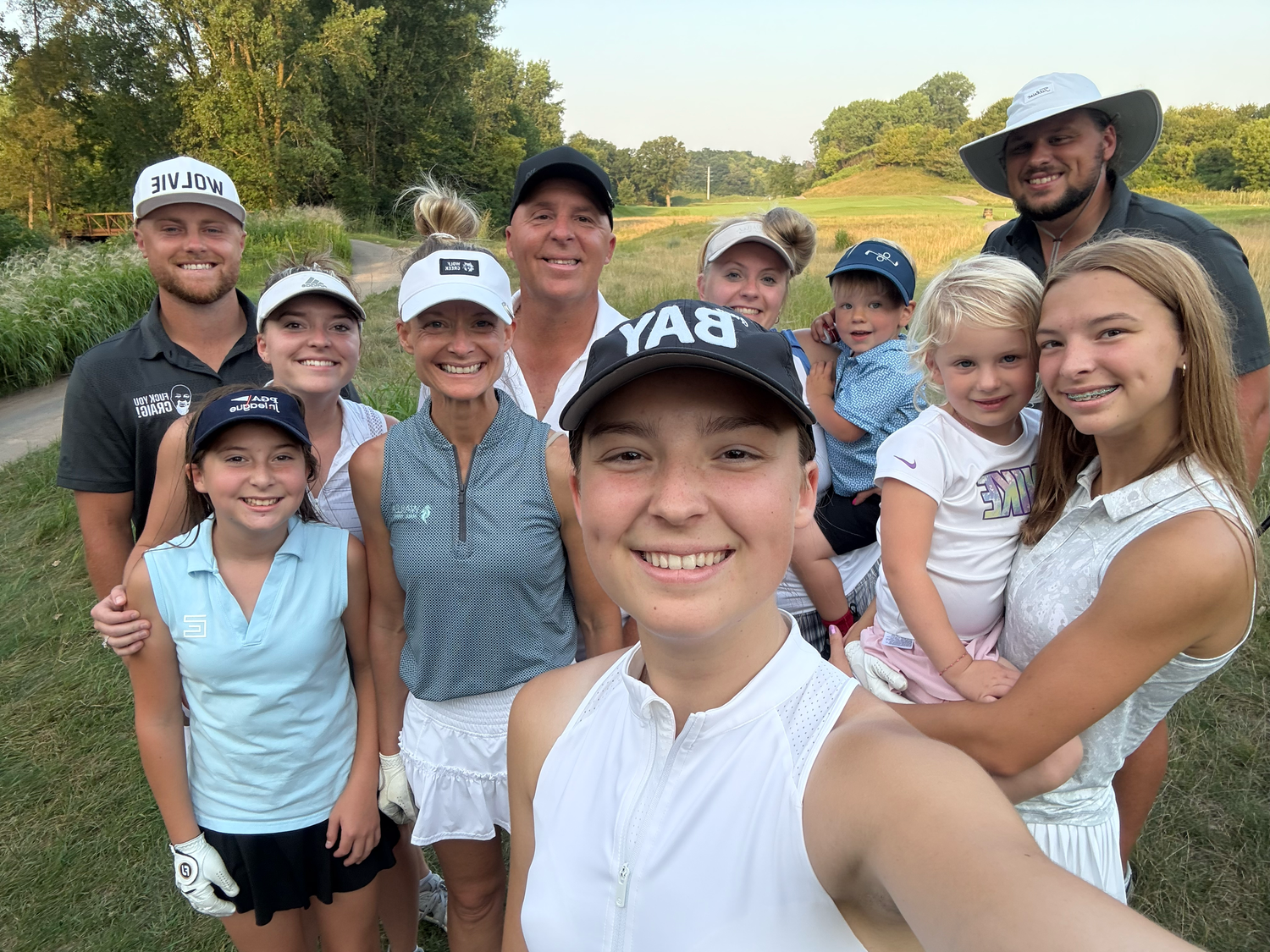 A group wearing golf attire poses together on a sunny course.
