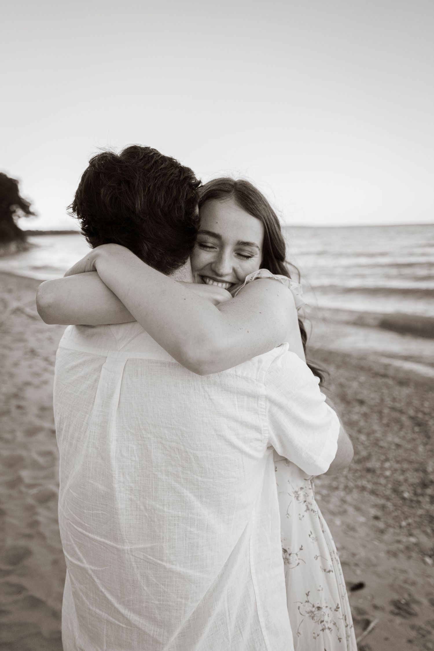 Intimate embrace on a beach shore in black and white photography.