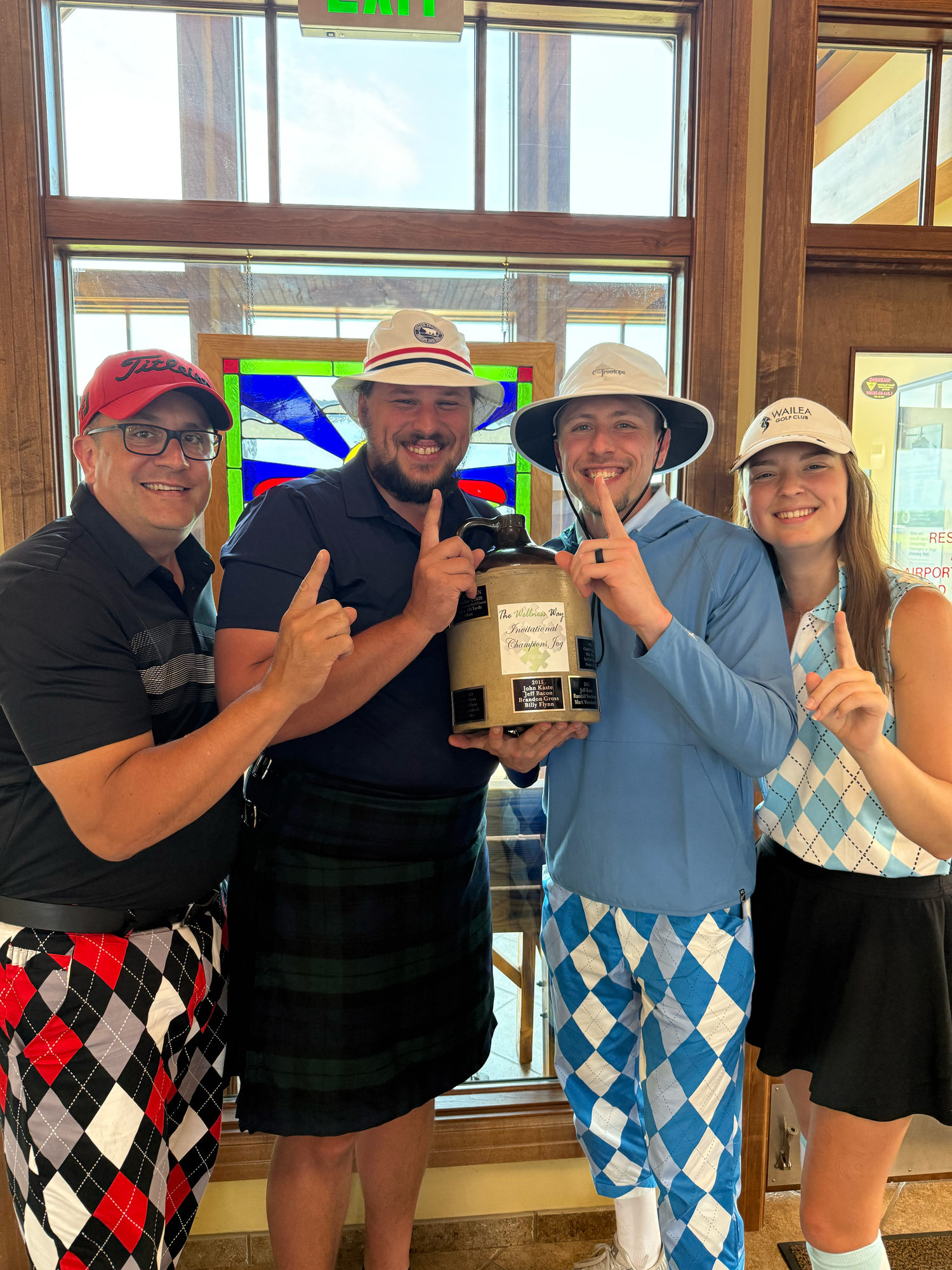 A group wearing matching argyle golf attire poses together indoors.