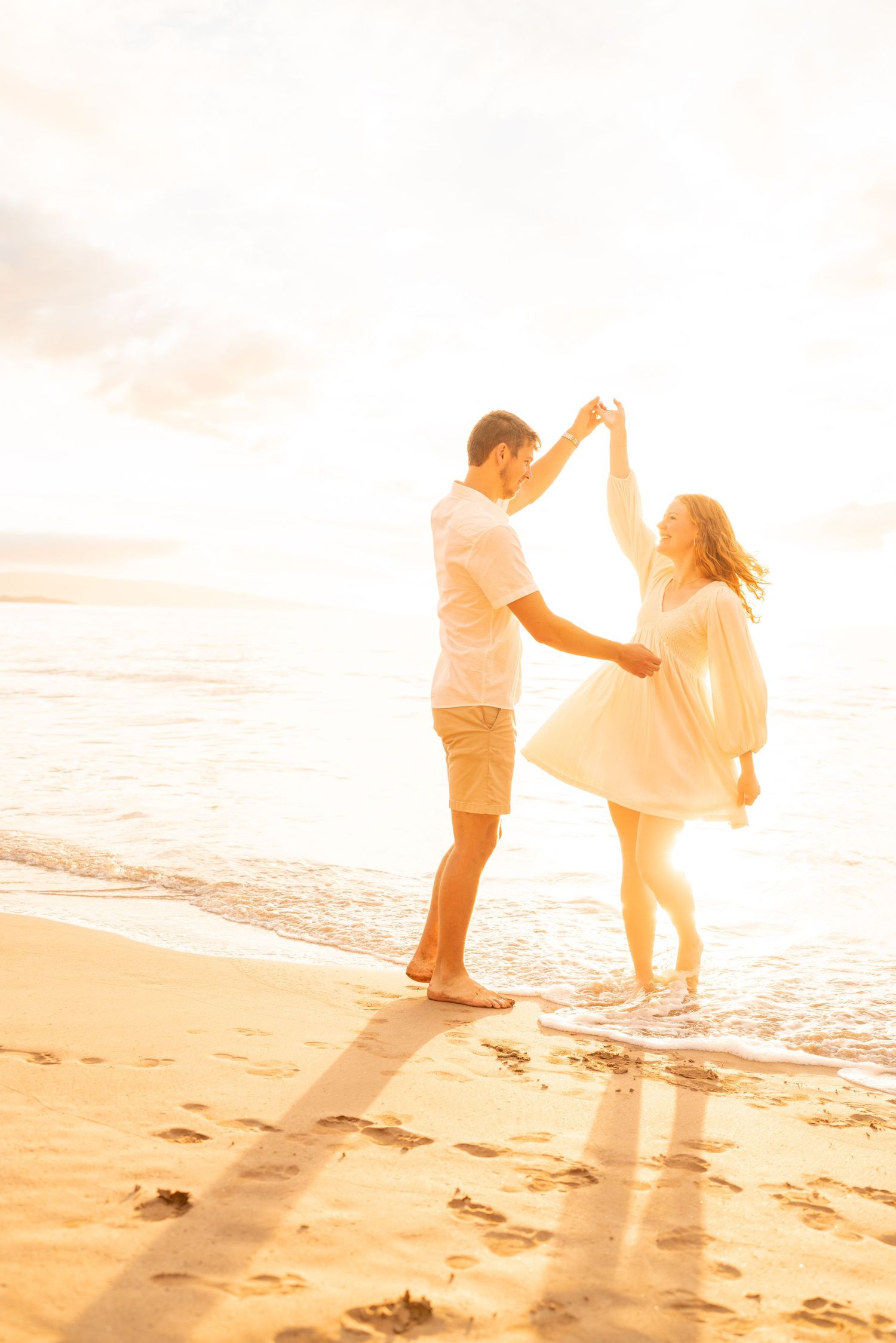 Dreamy beach photoshoot with couple dancing in soft golden sunlight.