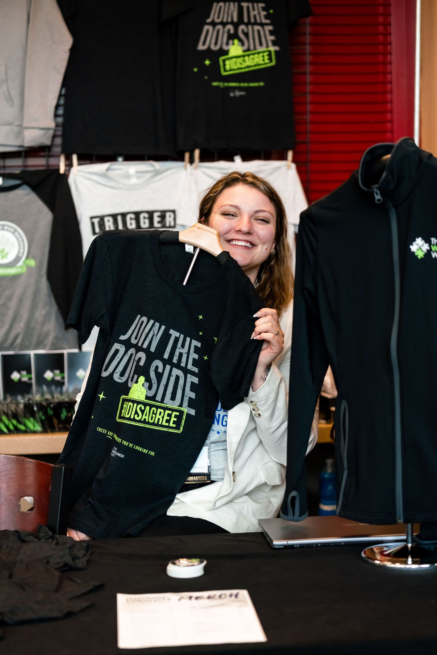 Merchandise display featuring dark t-shirts with 'Join the Dark Side' branding at an event.