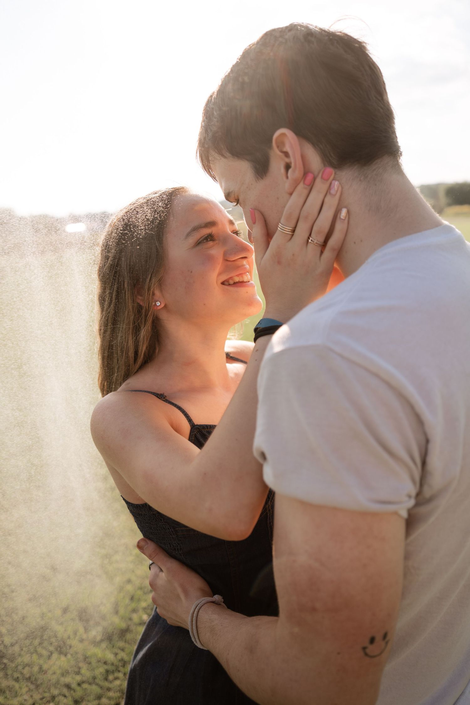 Romantic sunlit portrait captures couple's tender embrace against natural backdrop.