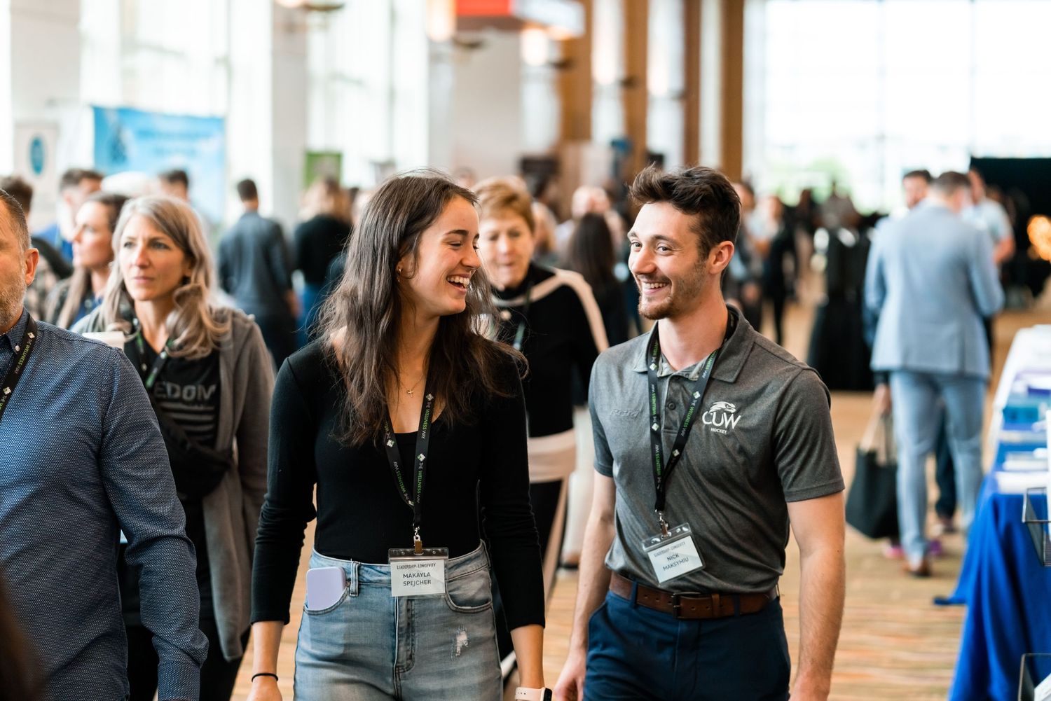 Conference attendees networking and mingling in a bright indoor venue during a business event.