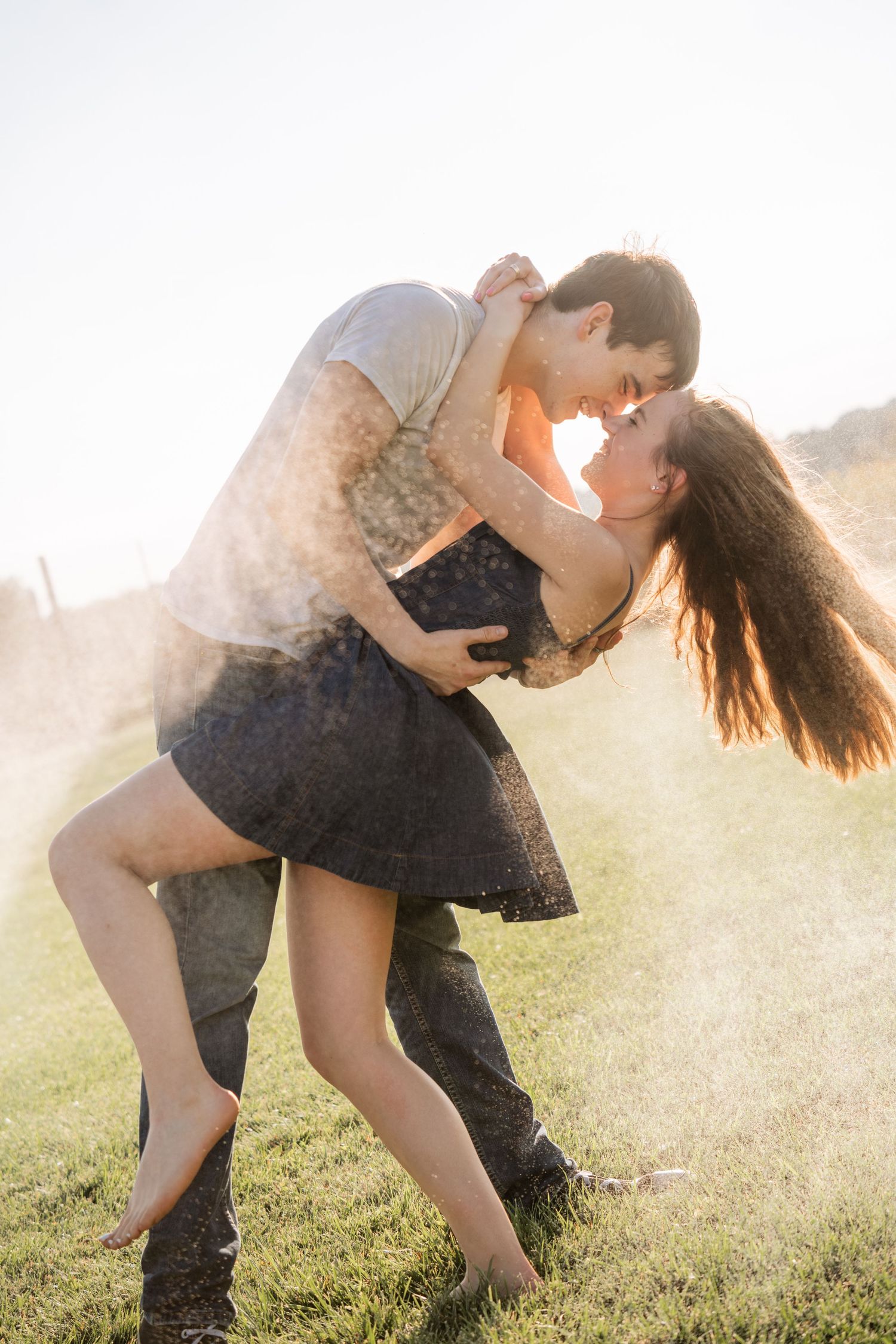 A romantic dip pose captured in golden sunlight on a grassy field.
