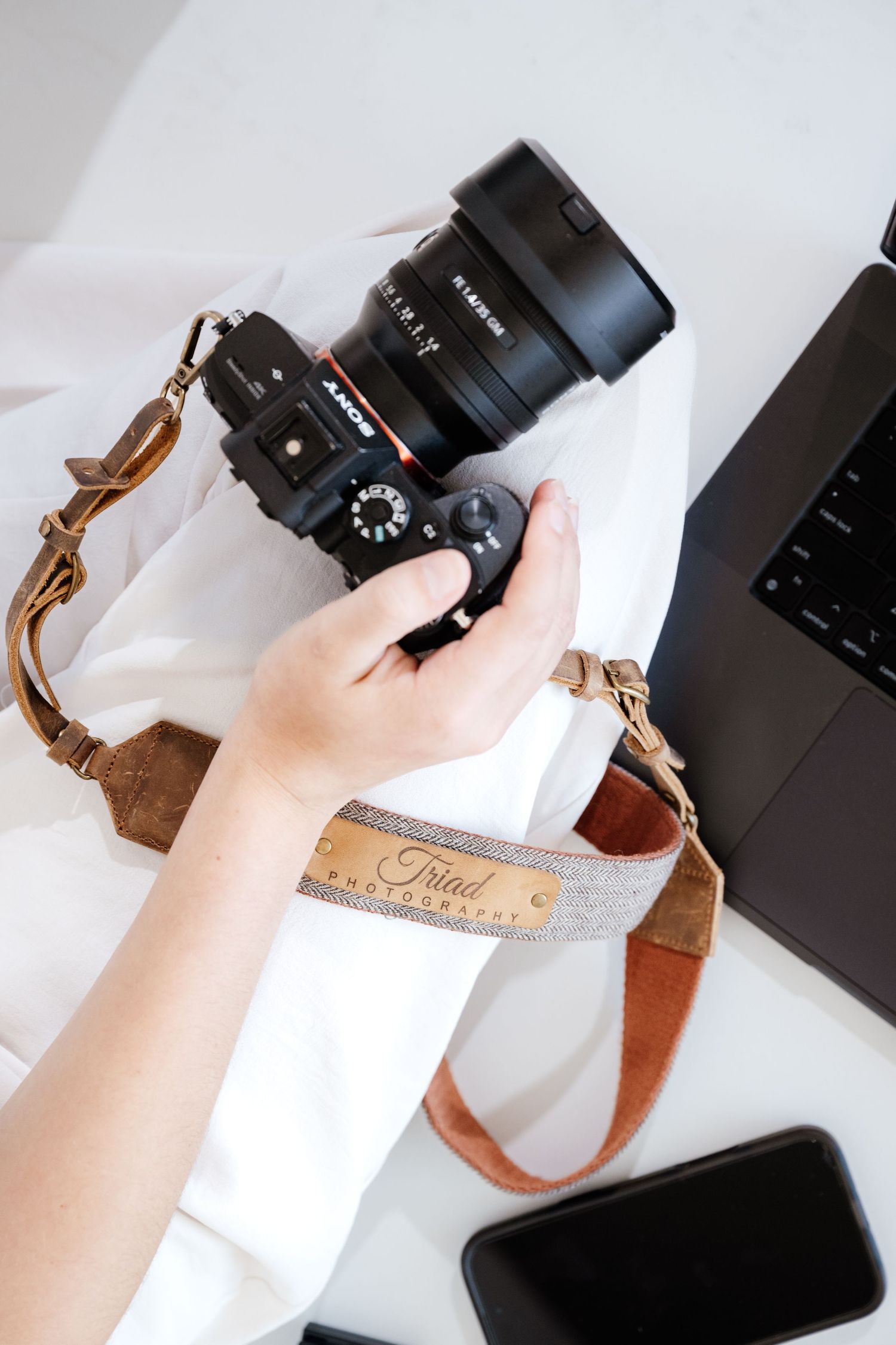 Detailed product shots of camera equipment and leather strap on white surface.