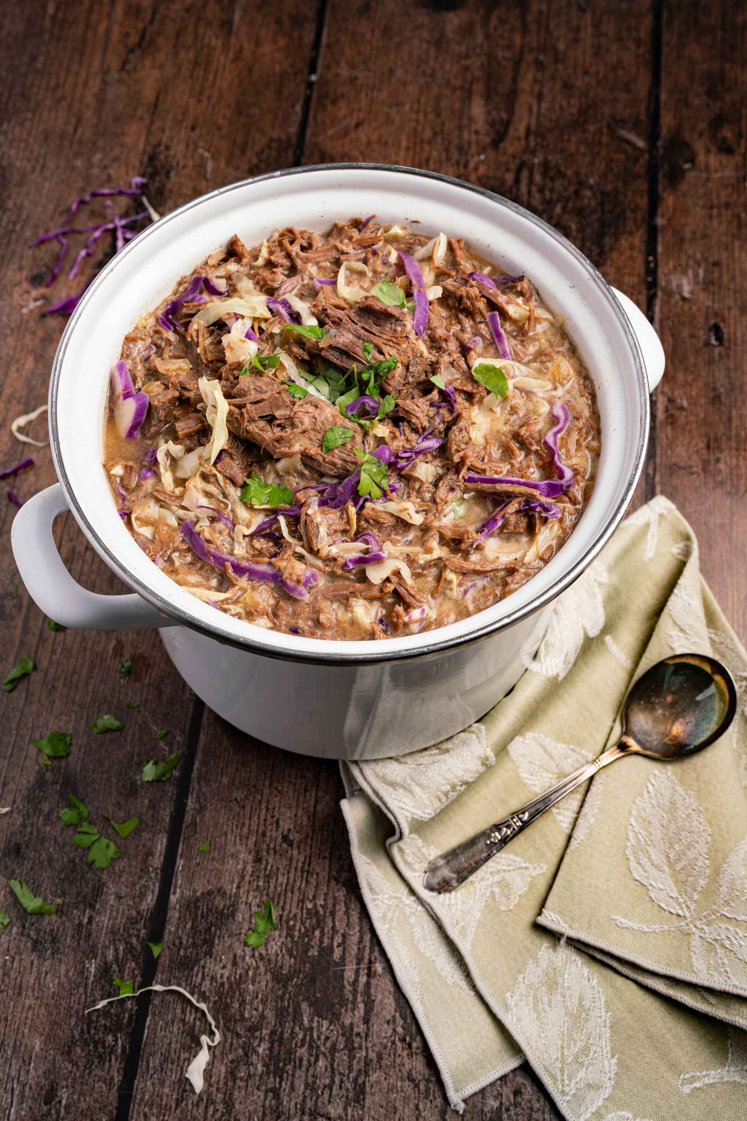 Creamy casserole topped with purple cabbage and fresh herbs in a white ceramic dish on rustic wood.