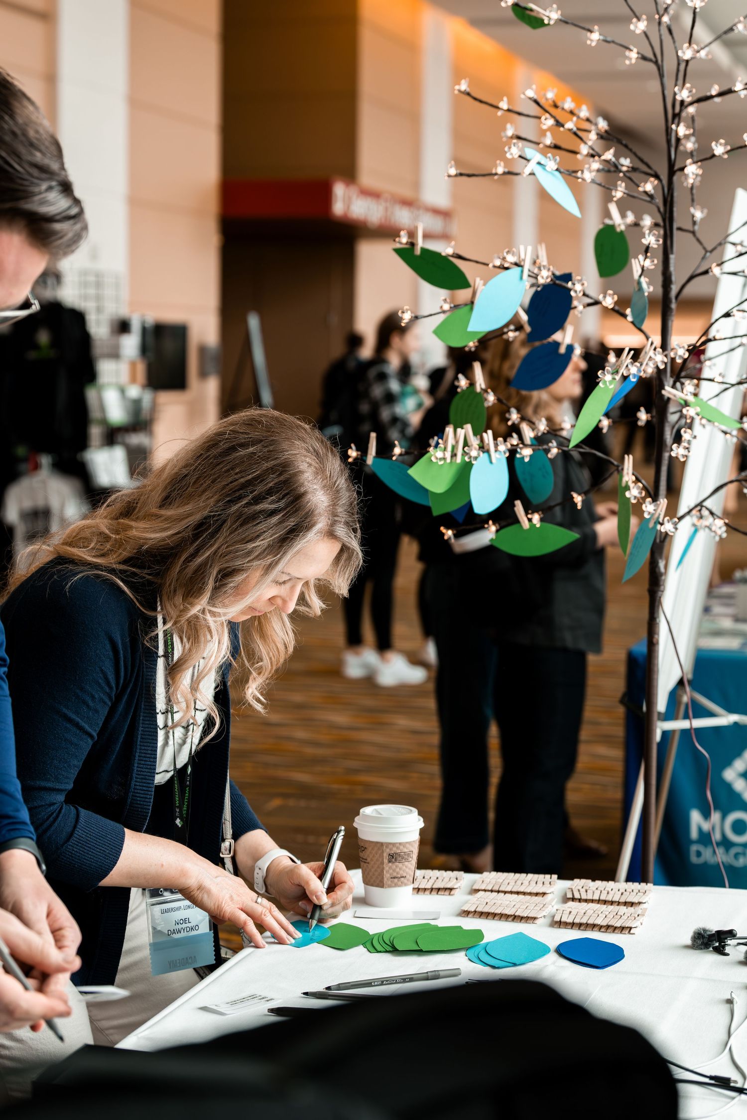 Craft activity station with decorative tree and colorful paper ornaments at an event.