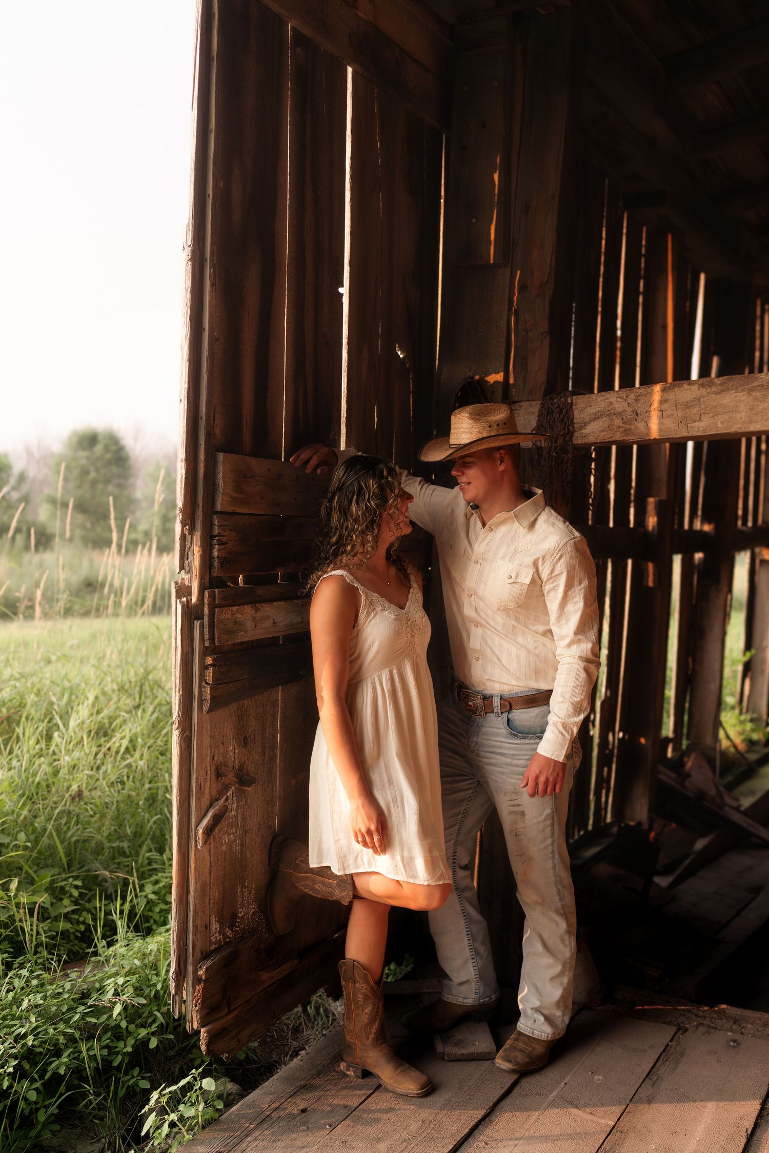 Artistic silhouettes and poses inside rustic barn with natural light streaming through.