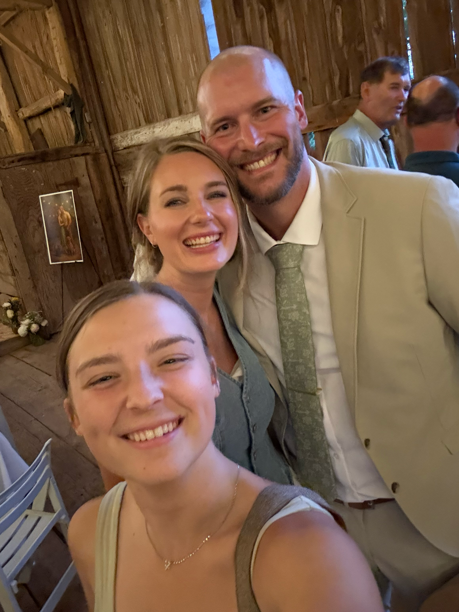 Wedding guests pose for photos inside a rustic wooden barn venue.