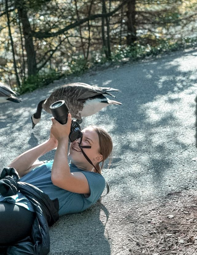 Photographer lying on ground taking creative angle shots outdoors.