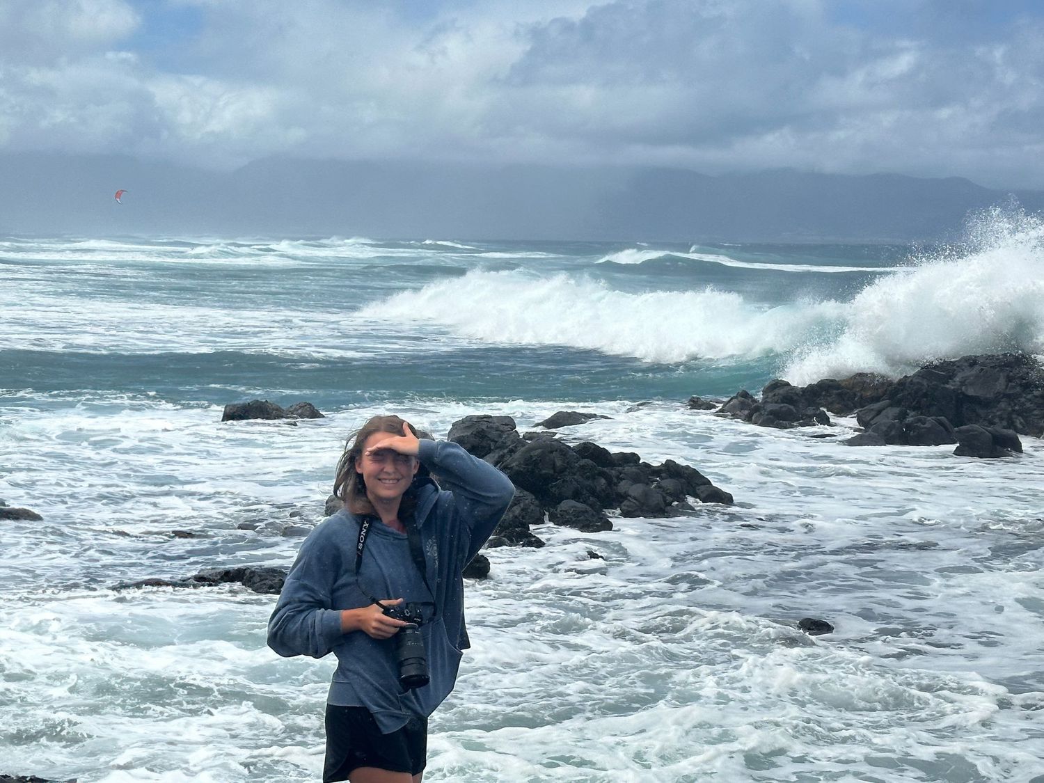 Dramatic ocean waves crash against rocky coastline on a stormy day.