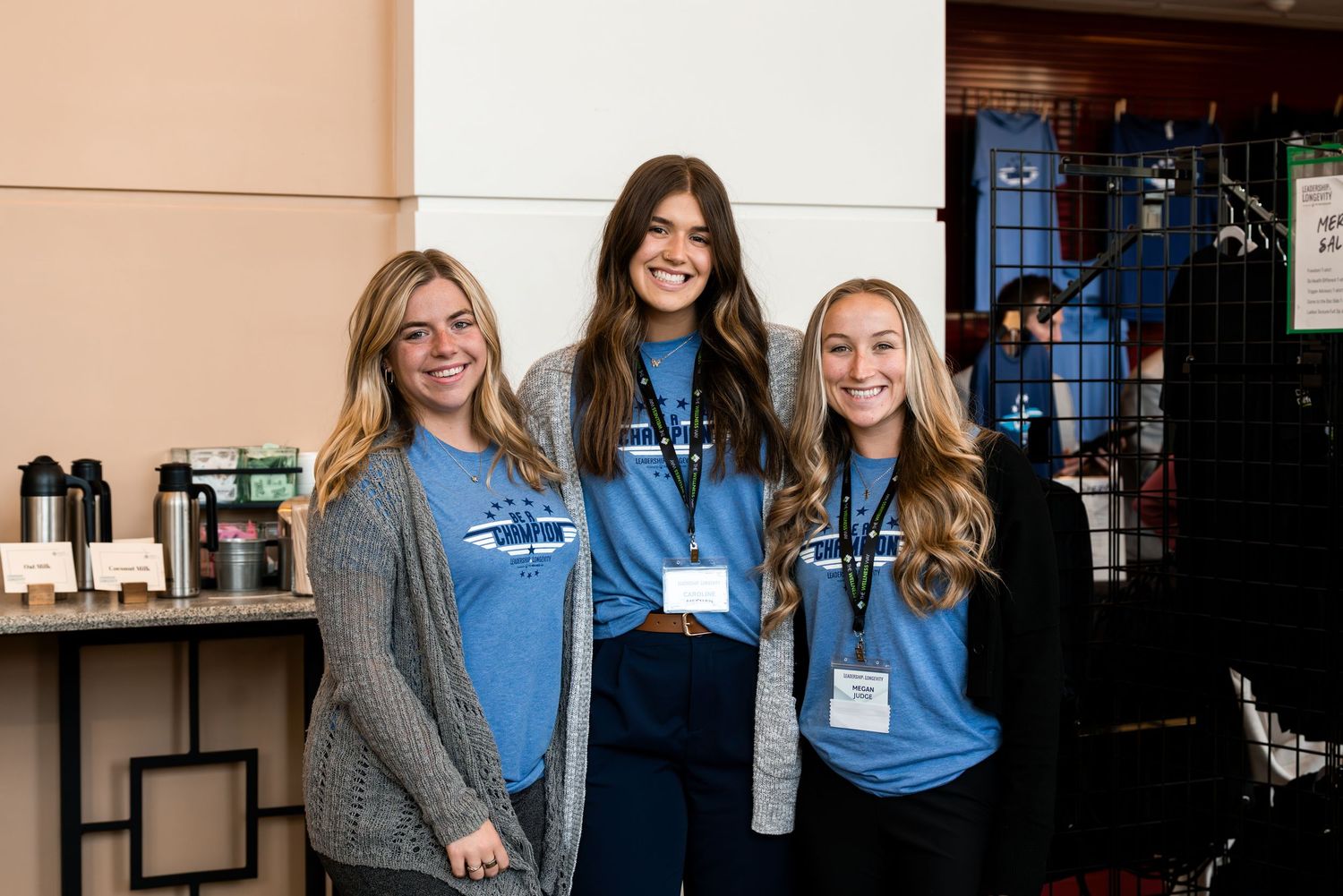 Conference attendees wearing blue shirts and name tags gather in a networking setting.