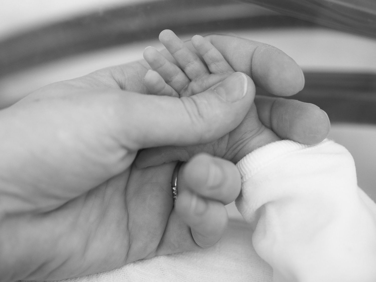 Reportage maternité sur la prématurité à l’APHP Necker : la main d’un bébé prématuré en couveuse dans celle de sa maman.