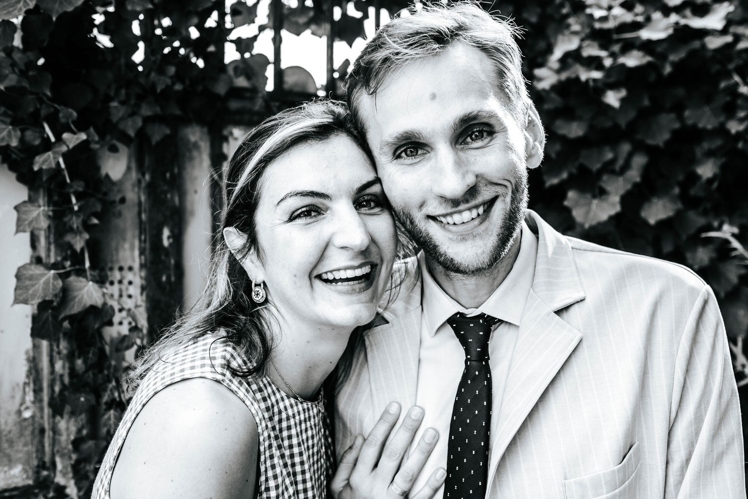 Happy couple smiling closely together in a black and white outdoor portrait photo.