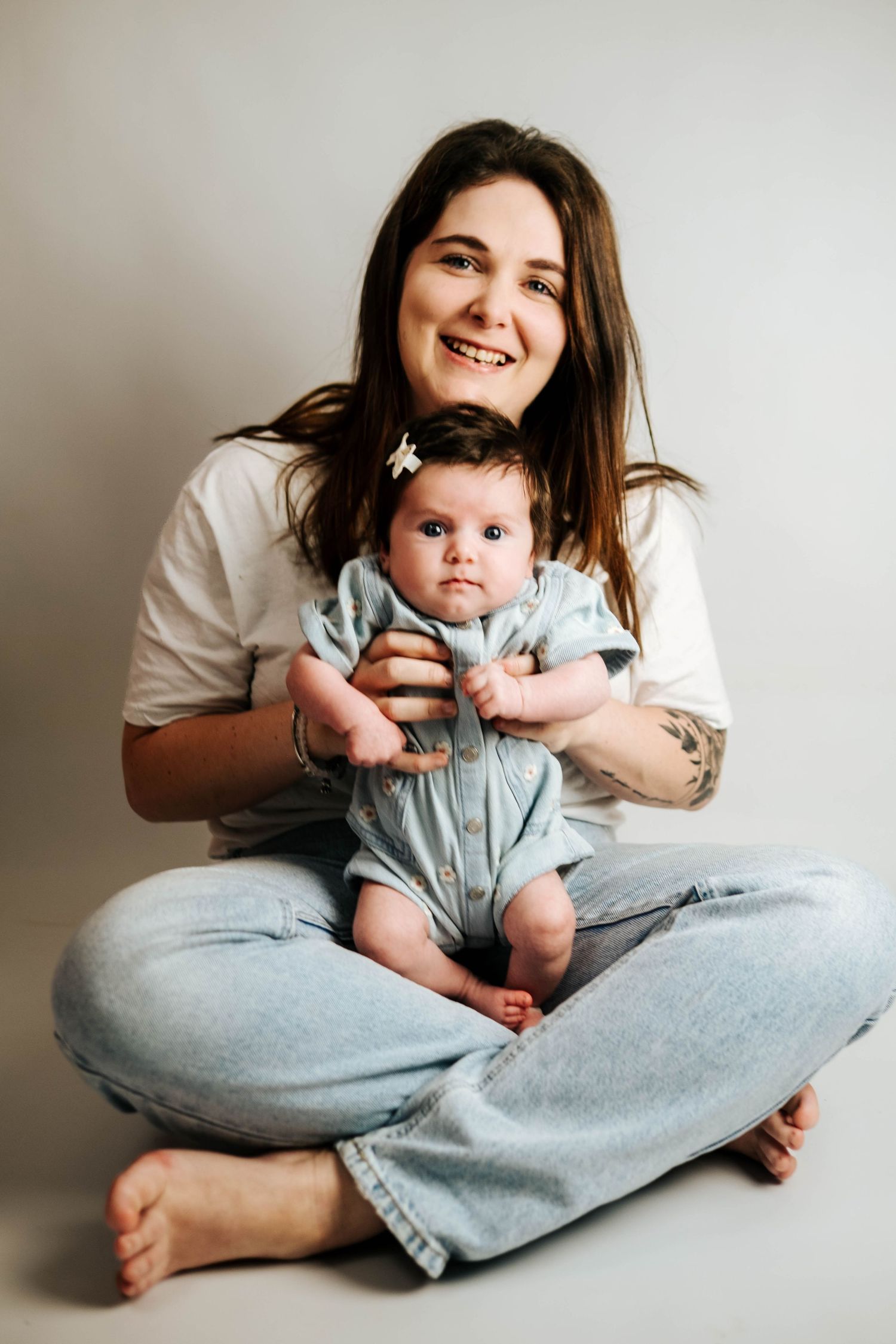 A heartwarming series of candid moments showing a parent and baby playing together against a light gray backdrop.
