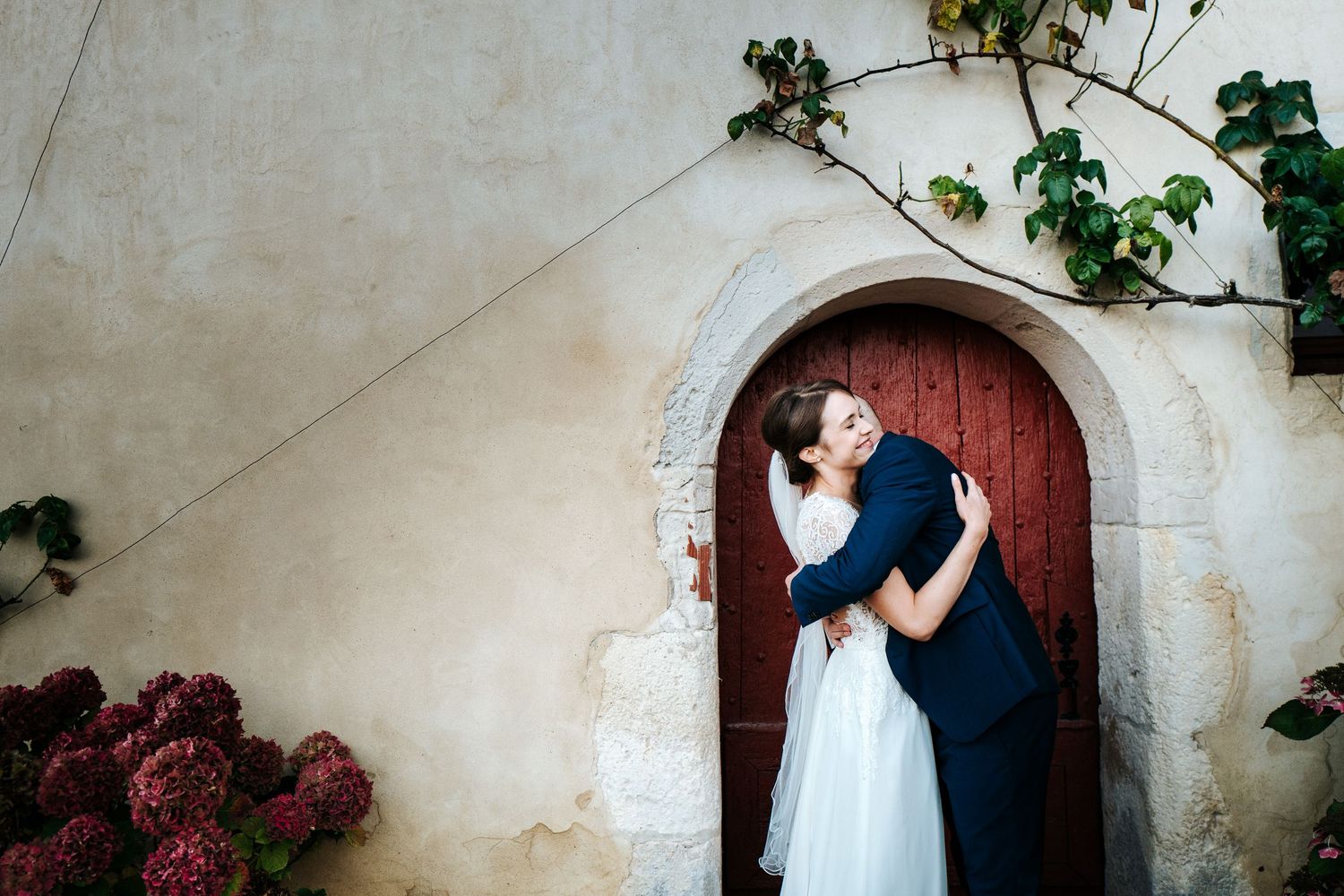 Romantic couple portraits against stone walls and floral gardens in an elegant outdoor setting.