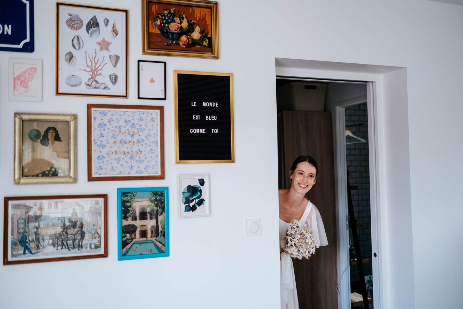 White wall decorated with various framed artwork and photographs in an eclectic arrangement.