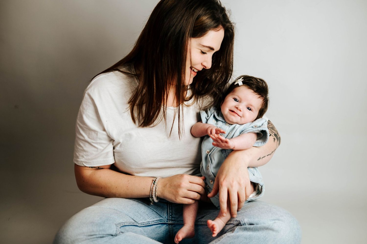 A series of tender moments between parent and newborn baby shown in black and white photographs against neutral backgrounds.
