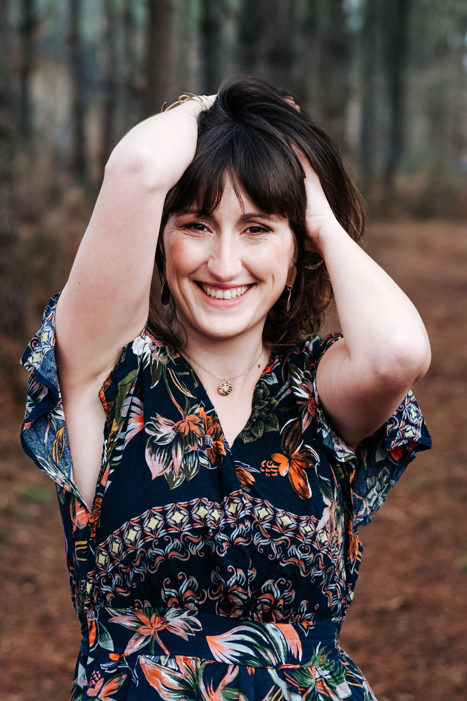 A person in a floral print dress poses playfully in a series of photos taken in an autumn forest setting.