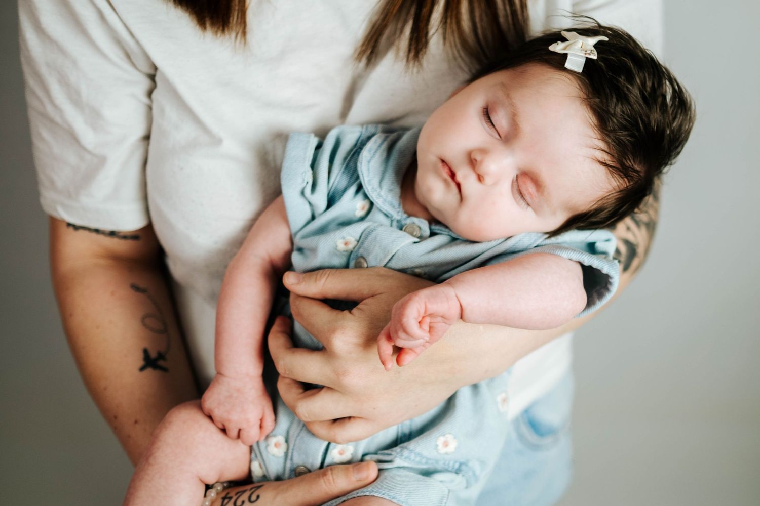 A series of seven intimate black and white photographs showing tender moments between parent and sleeping baby.