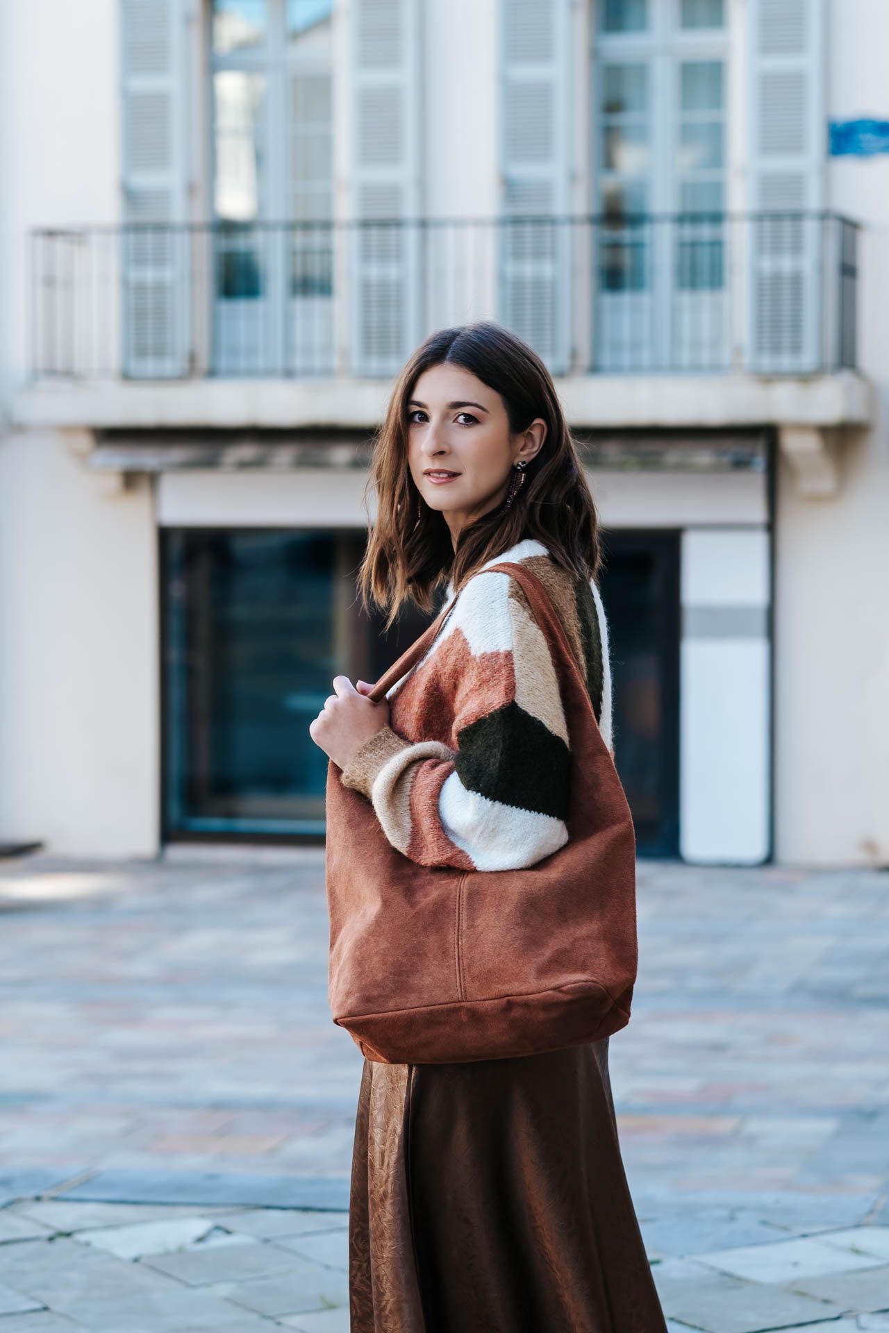 Fashion series showing brown suede bag styled with matching coat in urban setting.
