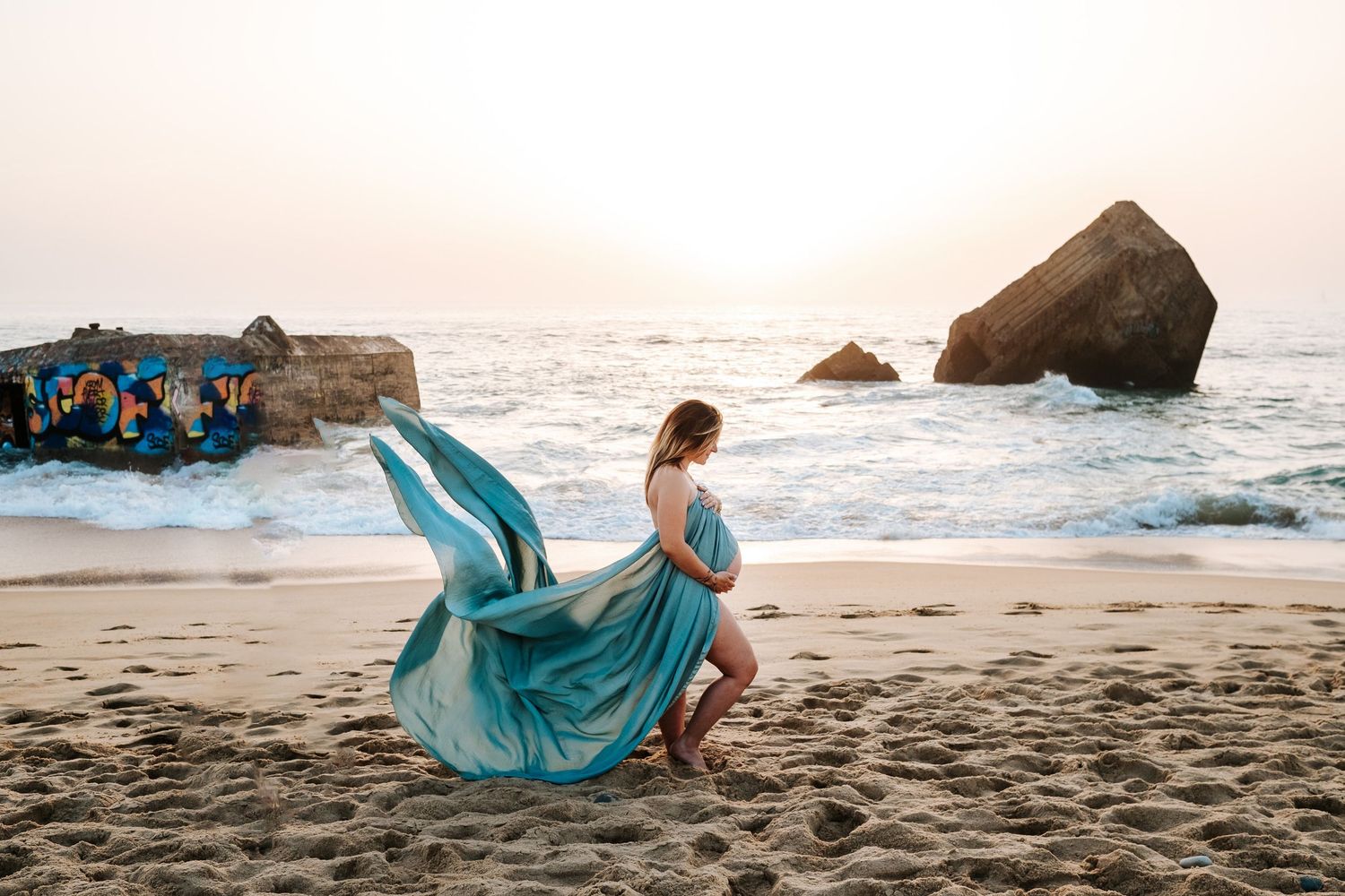 A series of beach photos featuring a flowing turquoise dress against dramatic coastal landscapes at sunset.