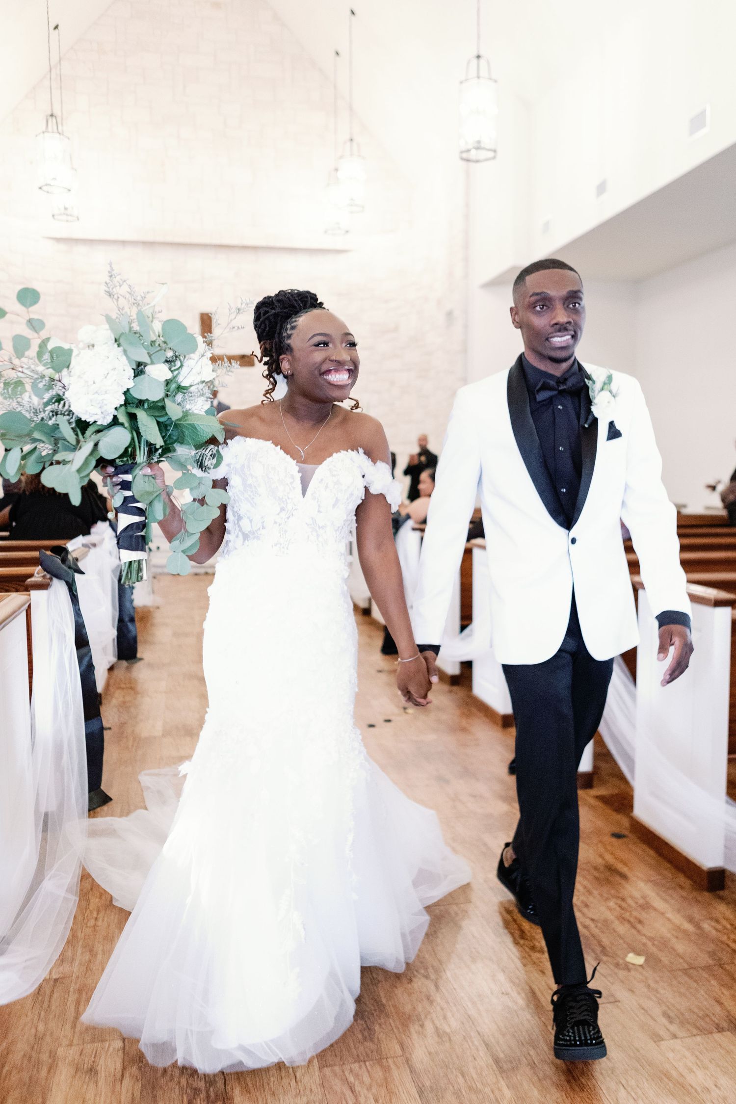 Dance floor at wedding reception with guests in formal white and black attire celebrating on hardwood floors.
