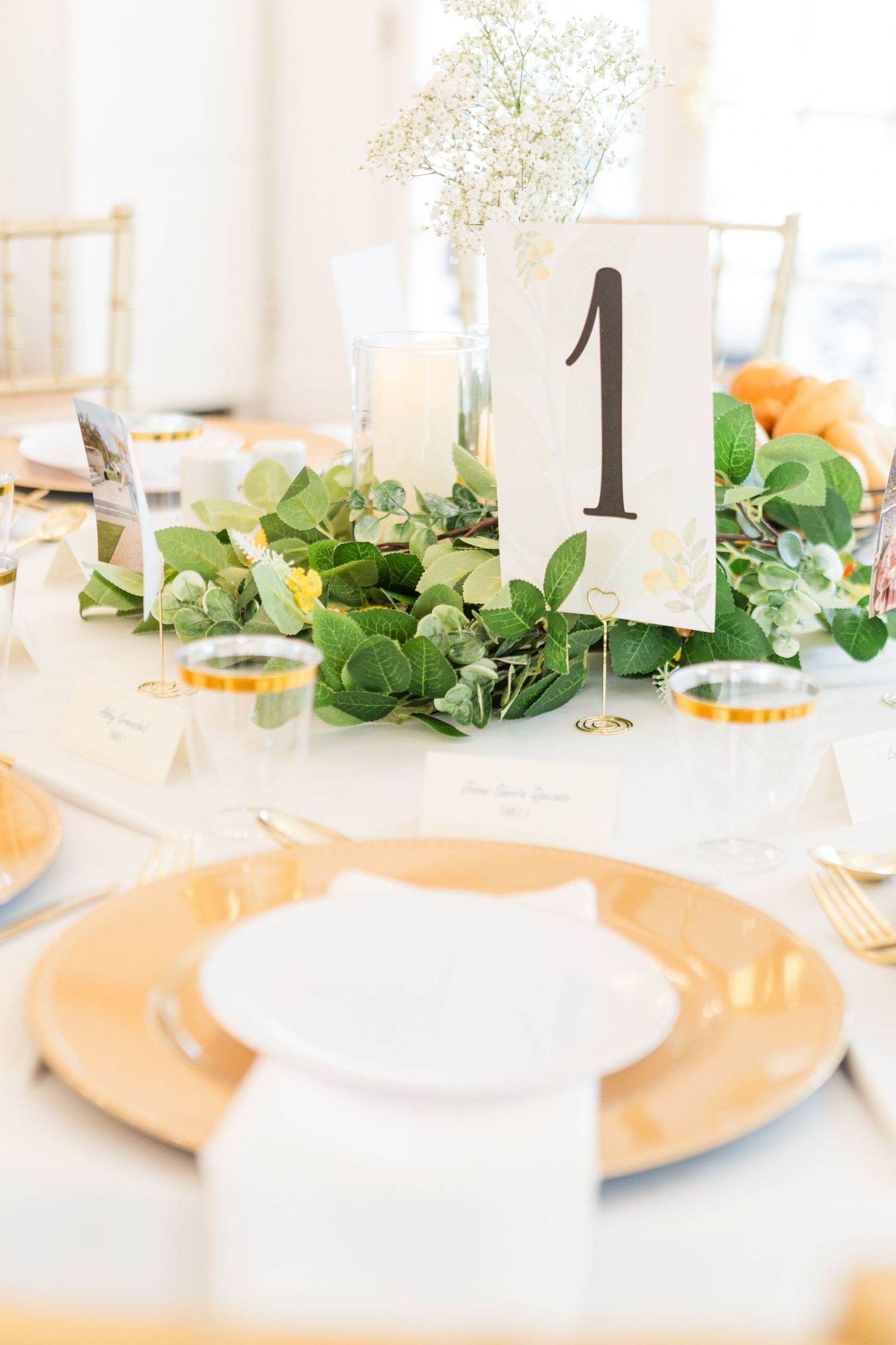 Elegant table setting with peach charger plates and green foliage decorations.