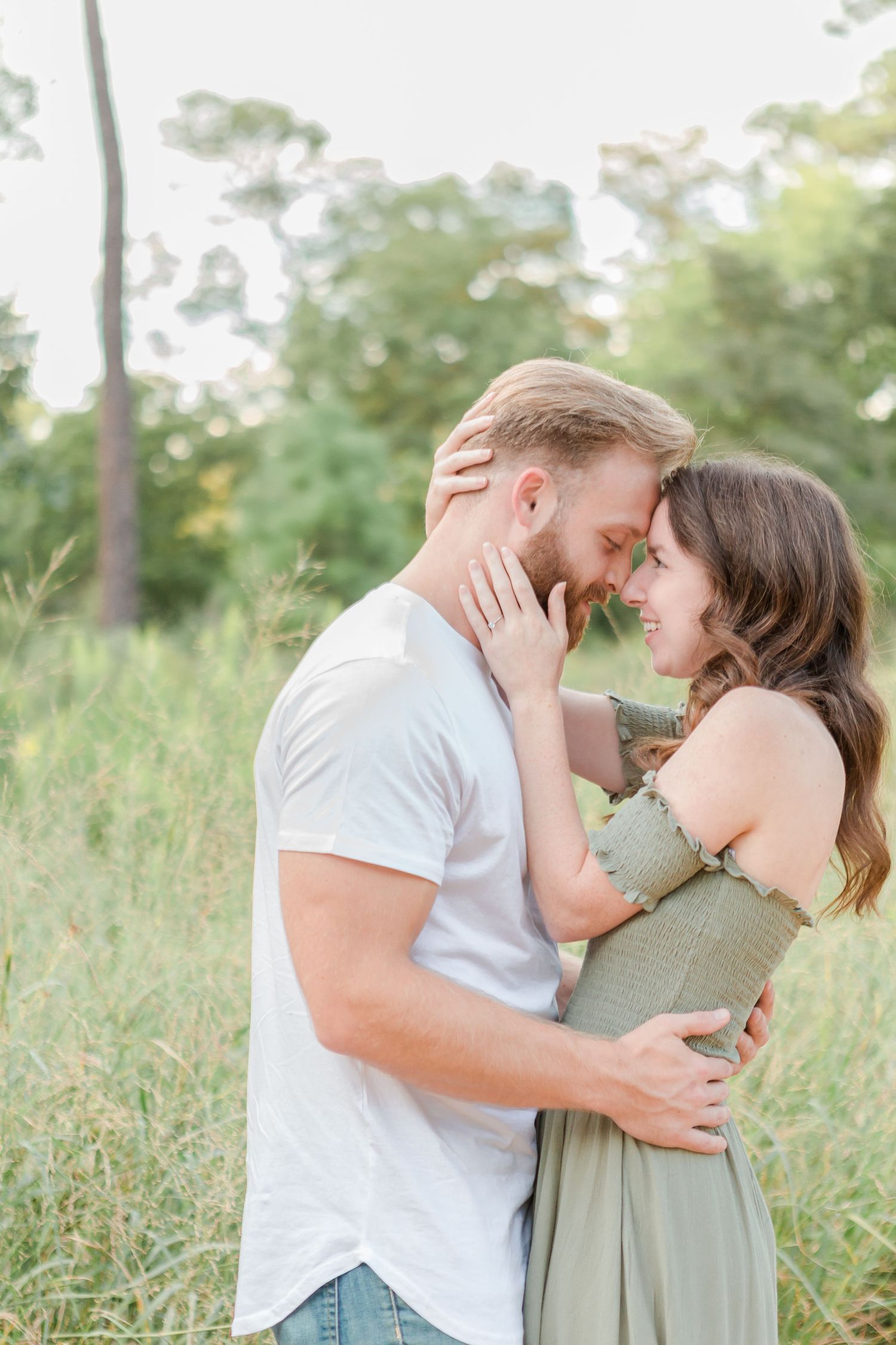 Couple embracing intimately on a wooded path surrounded by greenery.