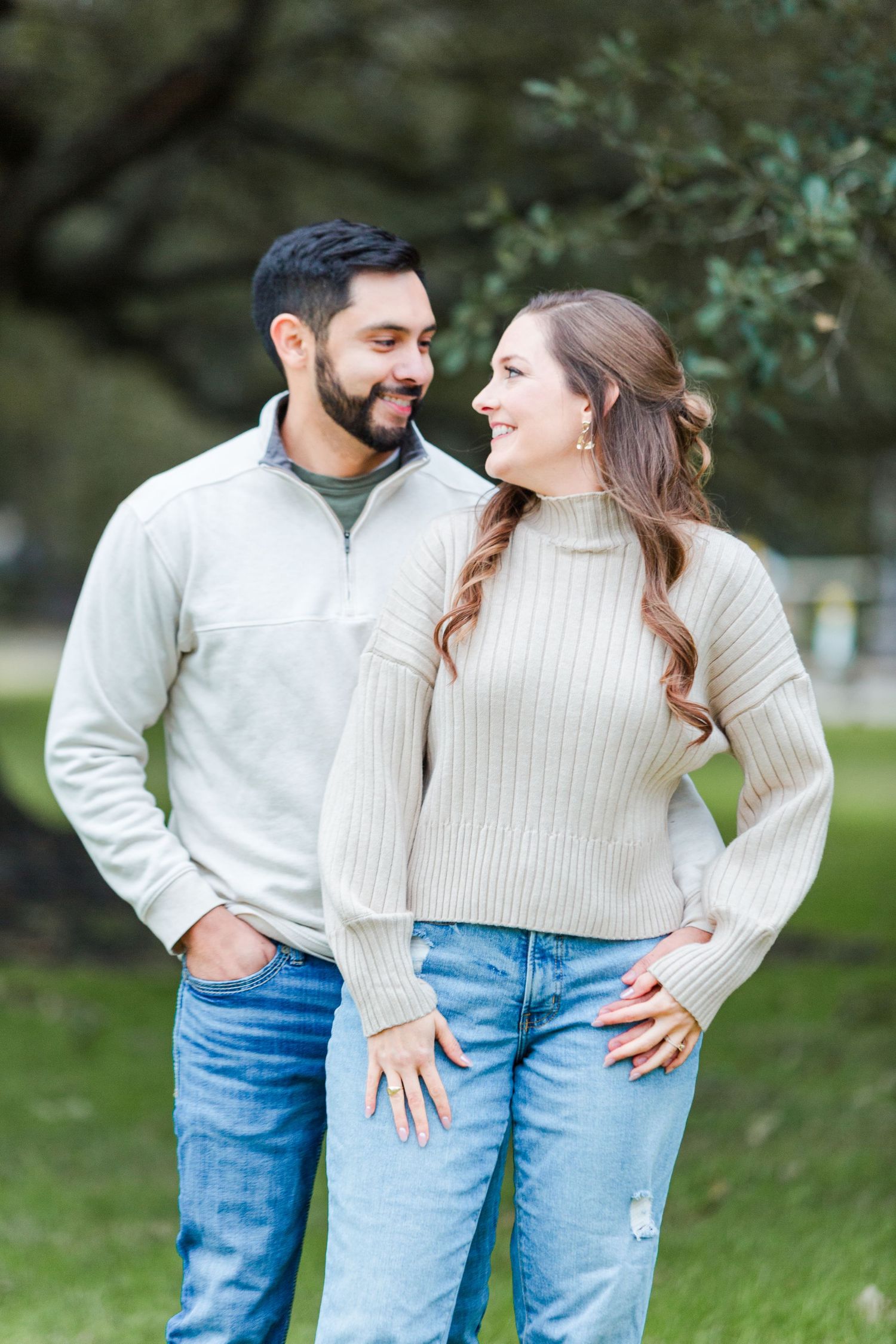 Affectionate couple in matching sweaters shares playful moment.