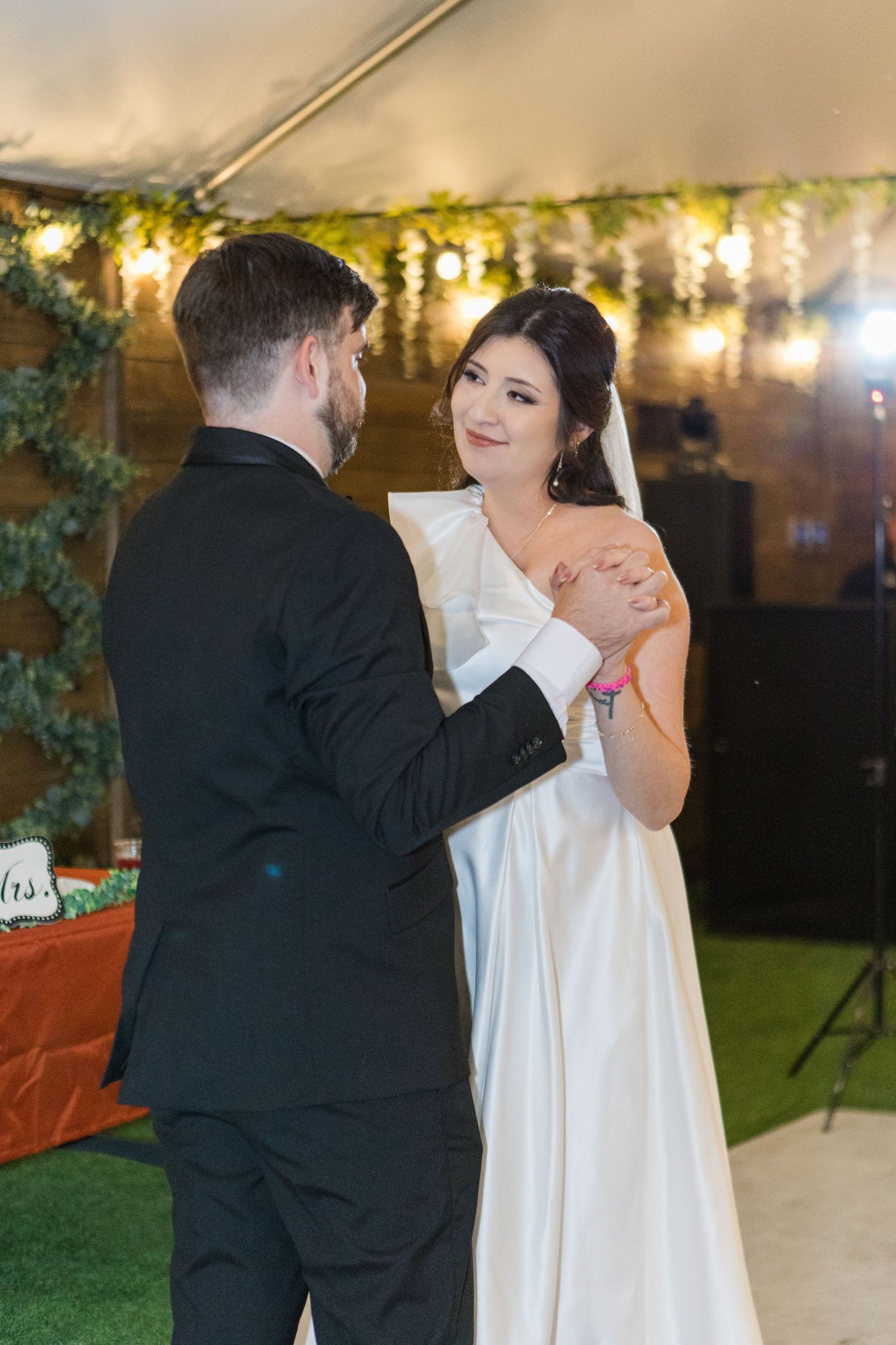 Newlyweds share their first dance under twinkling lights at evening reception.