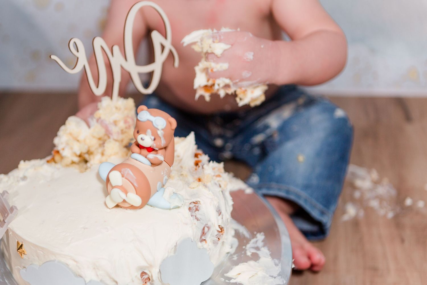 Scattered cake pieces and frosting during festive cake smash photoshoot.
