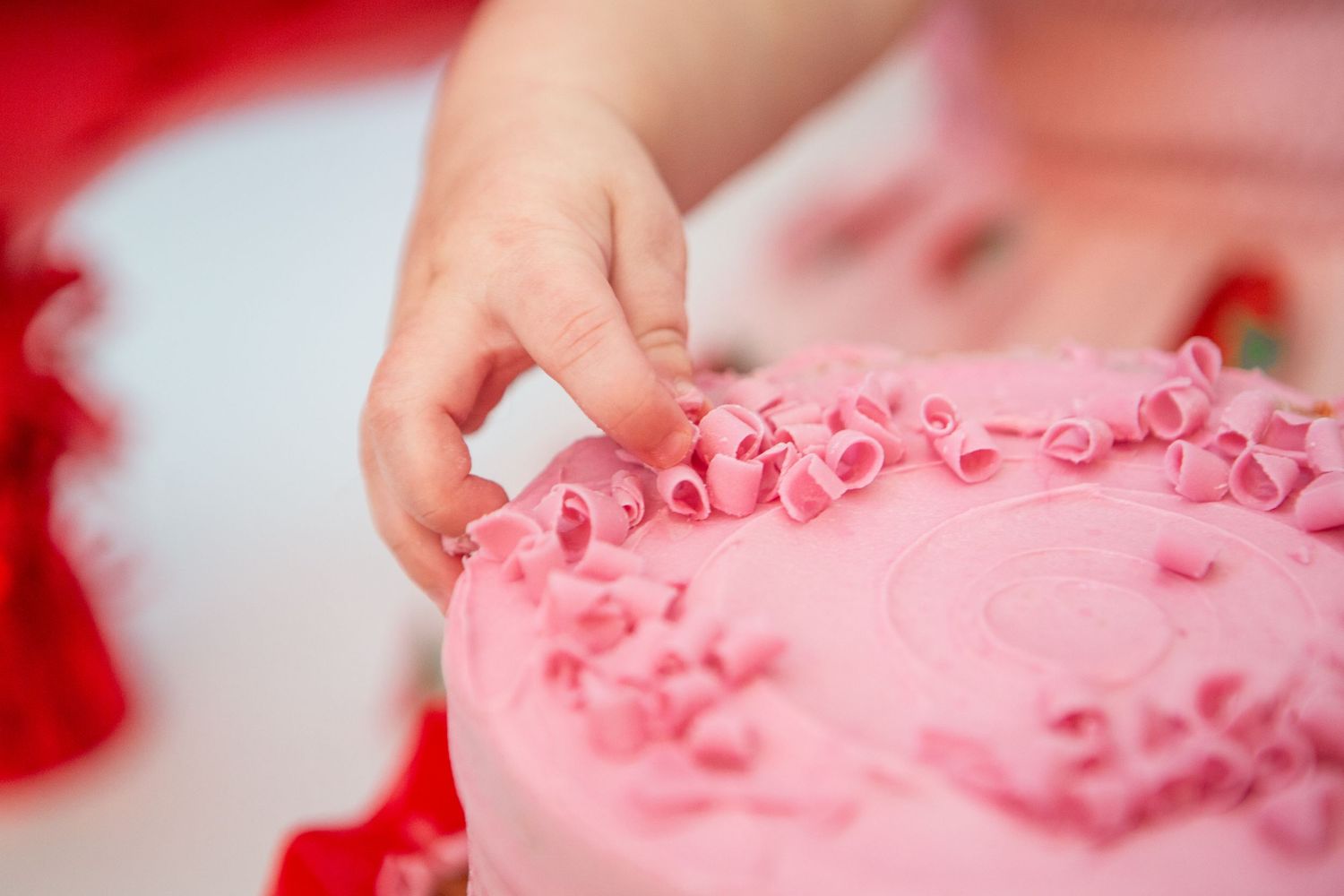 Close-up view of textured pink frosting and sprinkles on birthday cake.