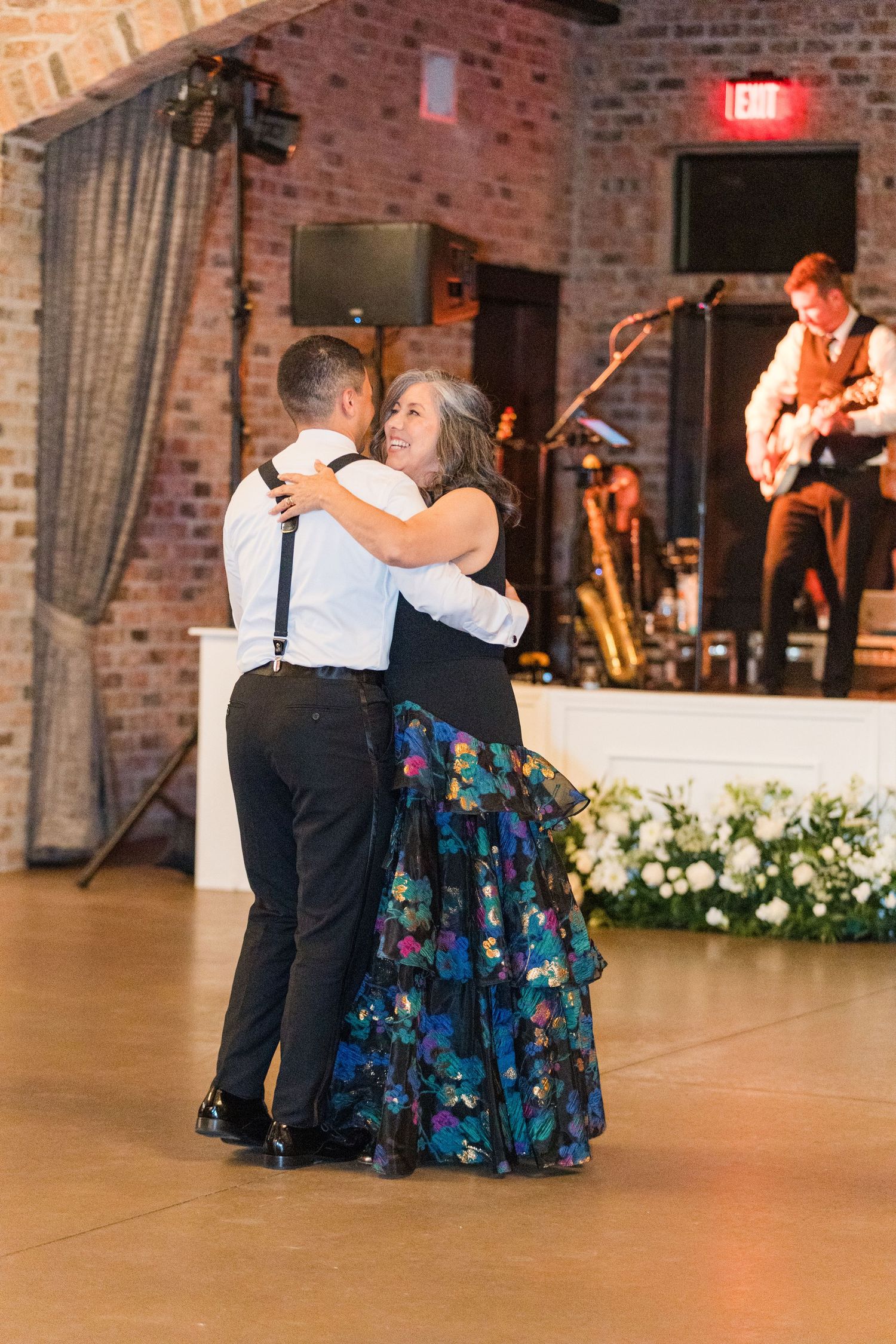 Dancers in formal wear and floral dresses performing at wedding reception.