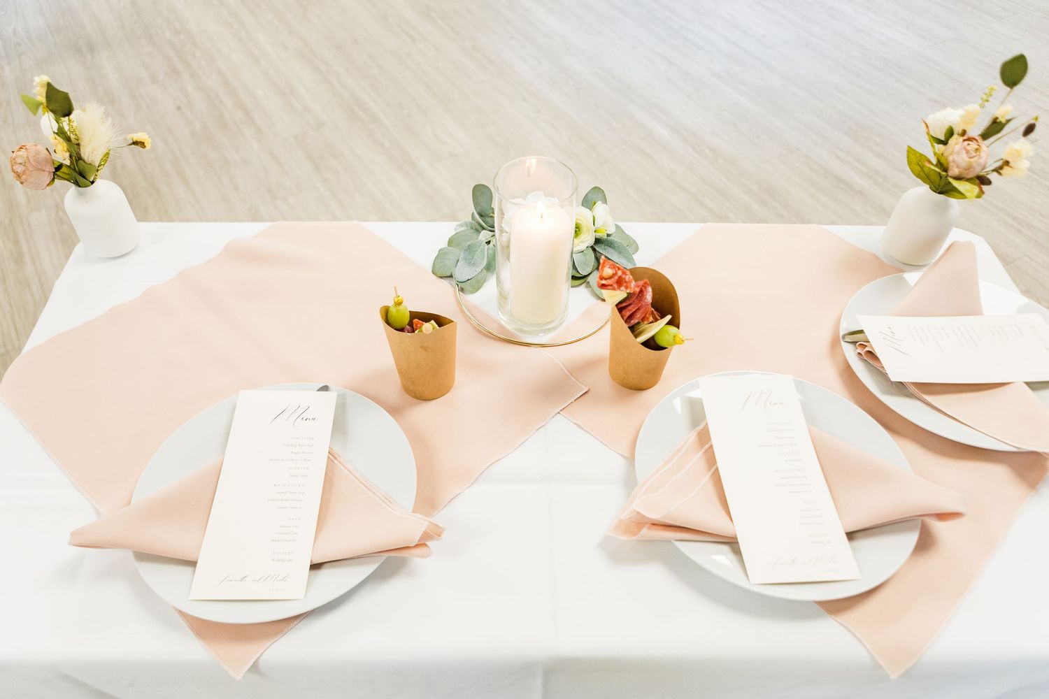 Wedding reception table with blush pink napkins and place settings.