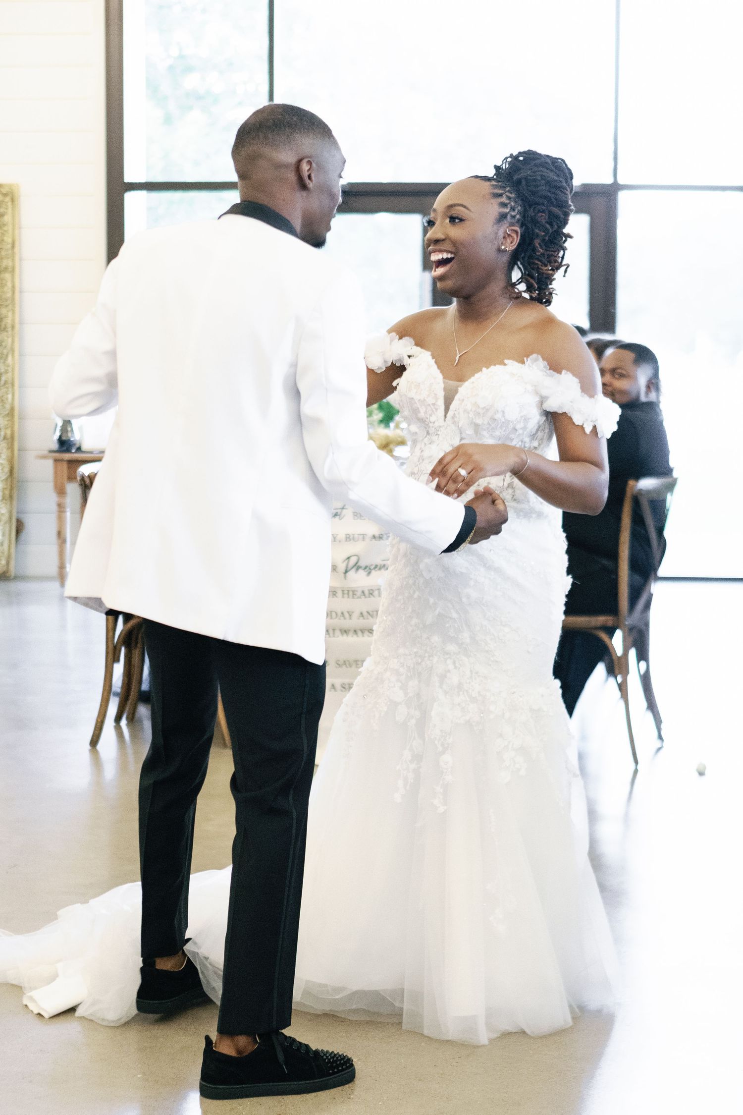 Candid wedding reception moments captured in a bright modern venue with white decor.