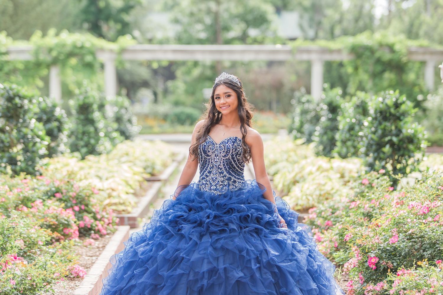 Royal blue ball gown with sparkly bodice photographed in a garden setting.