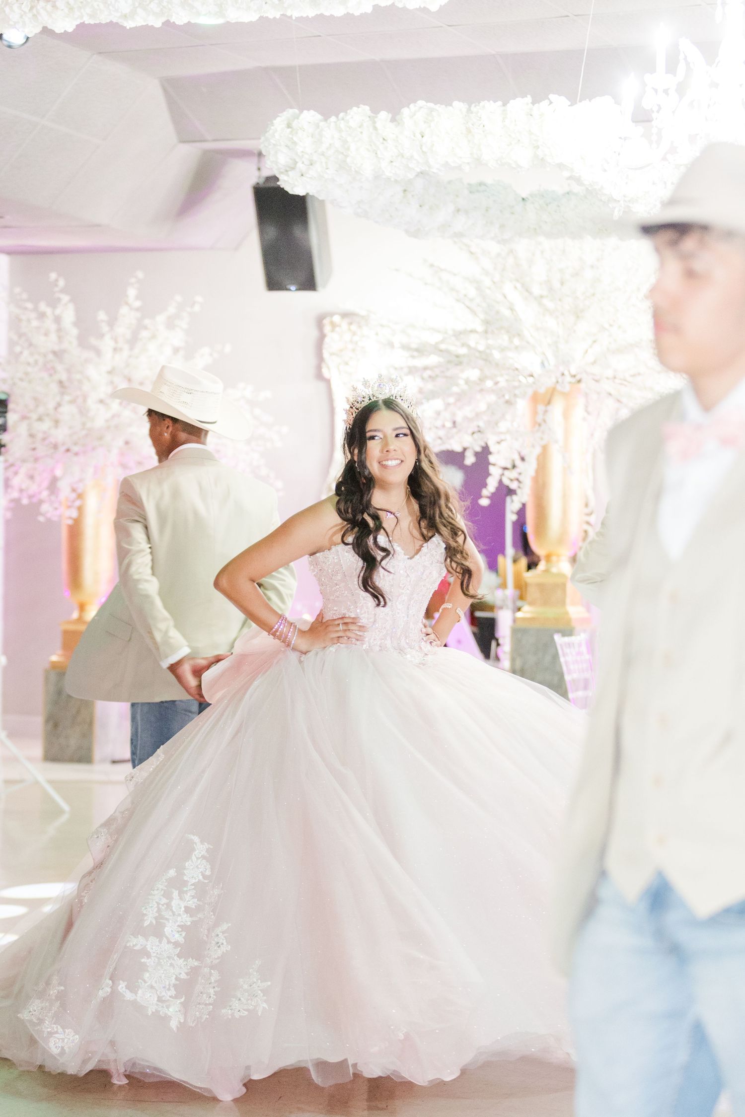 Stunning pose in a princess ball gown surrounded by white cherry blossom decorations and soft lighting.