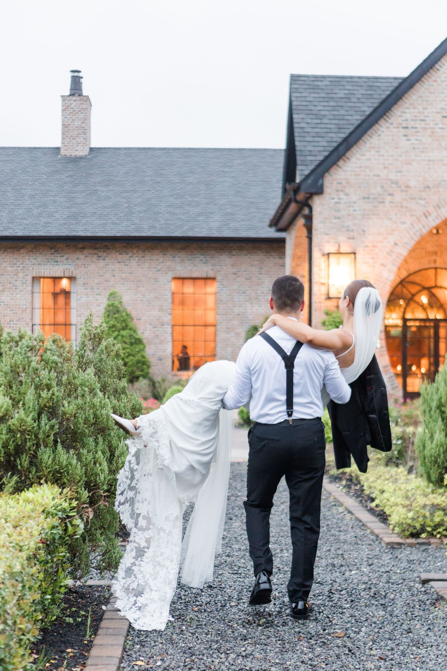 A sequence of wedding photos showing a couple walking along a gravel path outside a brick building at dusk.