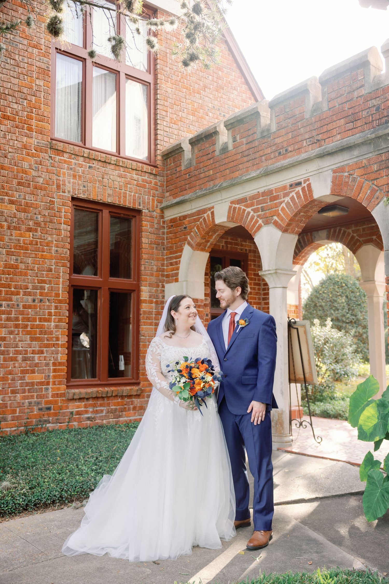 A couple shares romantic moments along a brick archway corridor at their wedding venue.