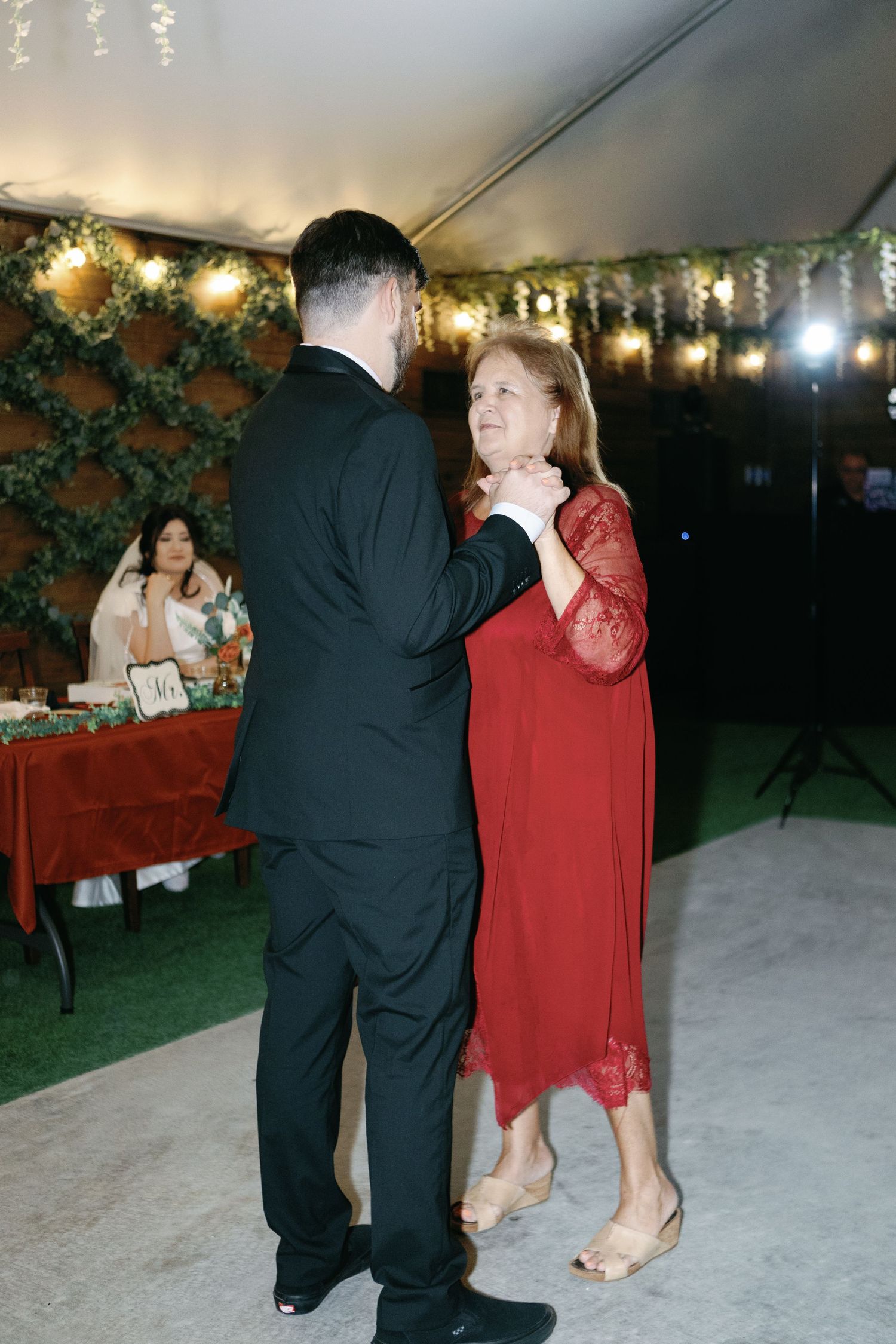 Couples dancing together at an outdoor evening wedding reception with string lights overhead.