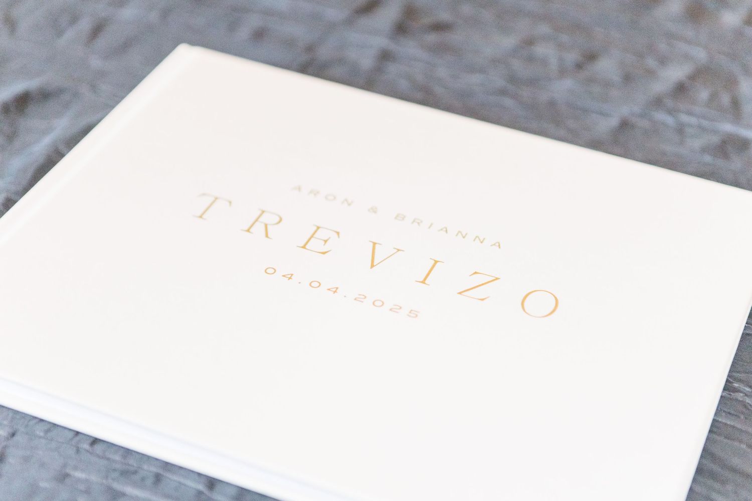 White wedding invitation with gold foil text reading Trevizo.