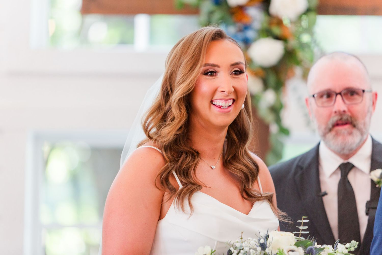 Bride in white wedding dress smiling during ceremony.