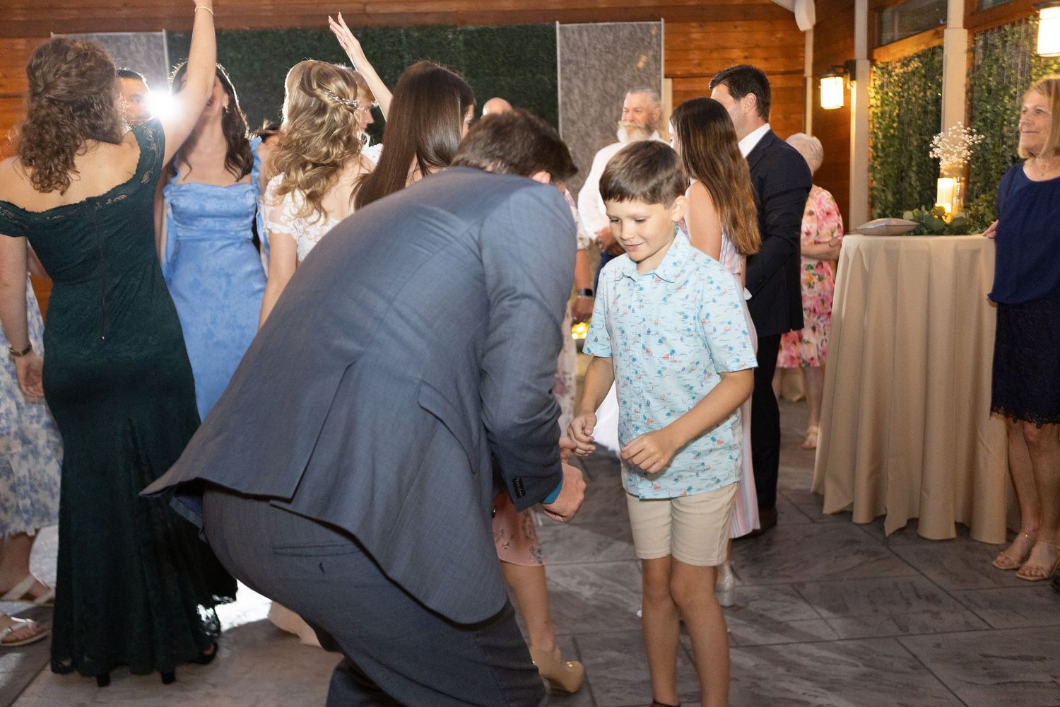 Wedding reception dance floor filled with guests celebrating under wooden rafters.