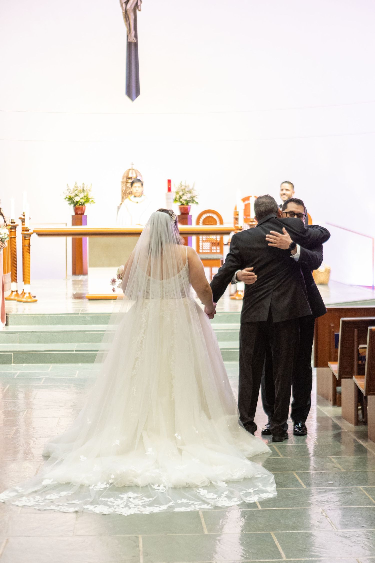 Wedding ceremony processional in a modern church with a dramatic trailing veil.