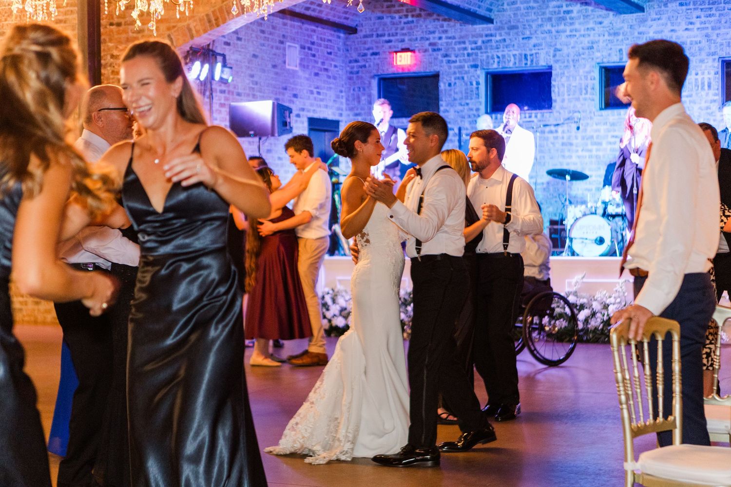 Wedding reception dance floor illuminated with blue and amber lighting against brick walls.