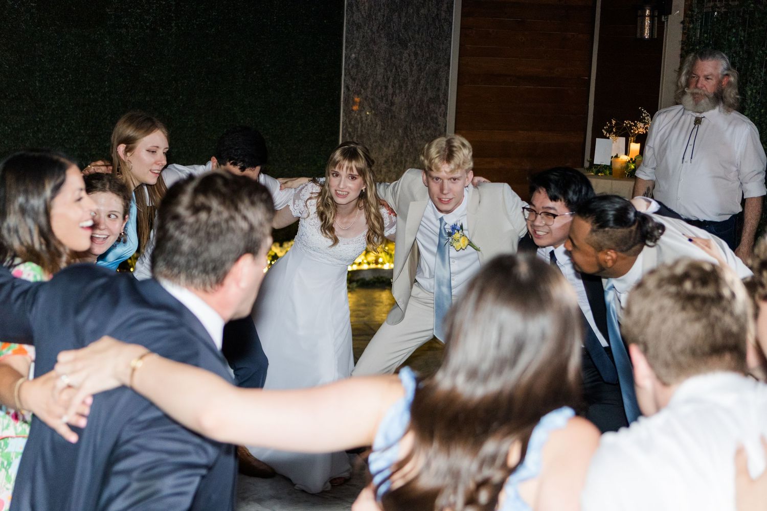 Dance floor filled with guests celebrating at an evening wedding reception.